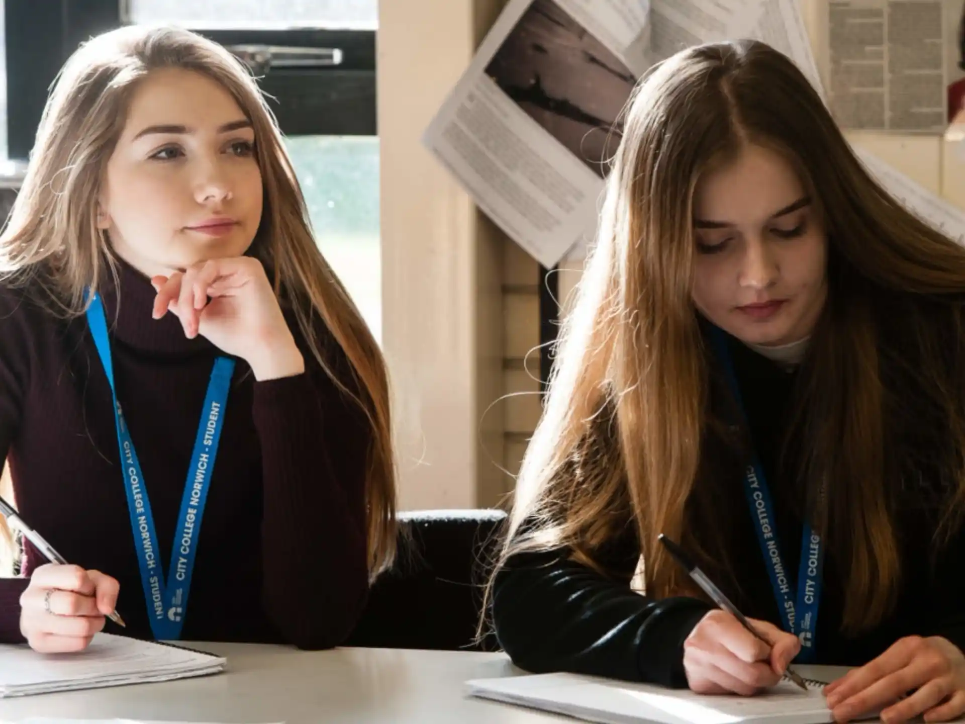 a couple of girls sitting at a table looking at the camera