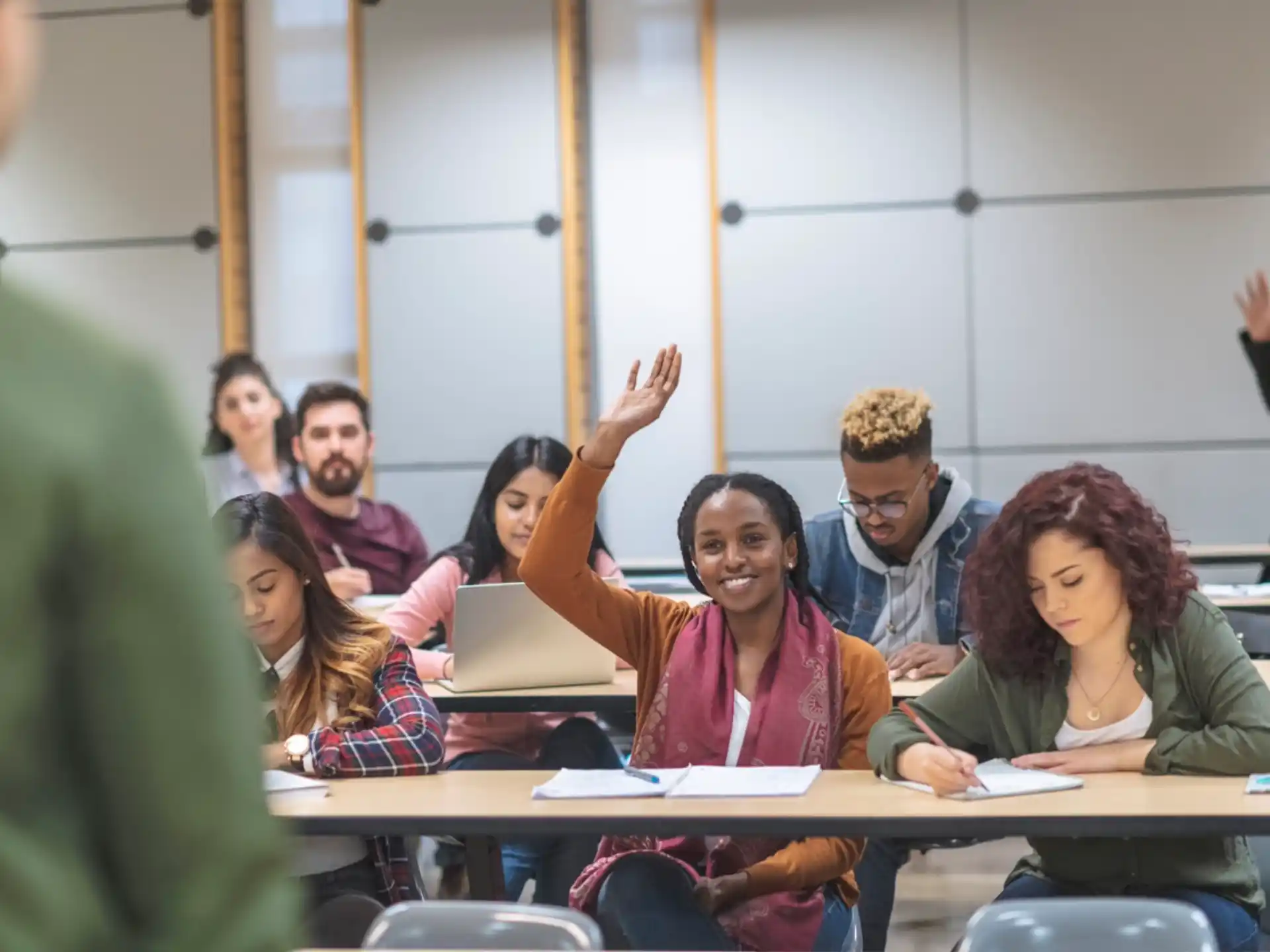 a group of people sitting at desks with their hands up