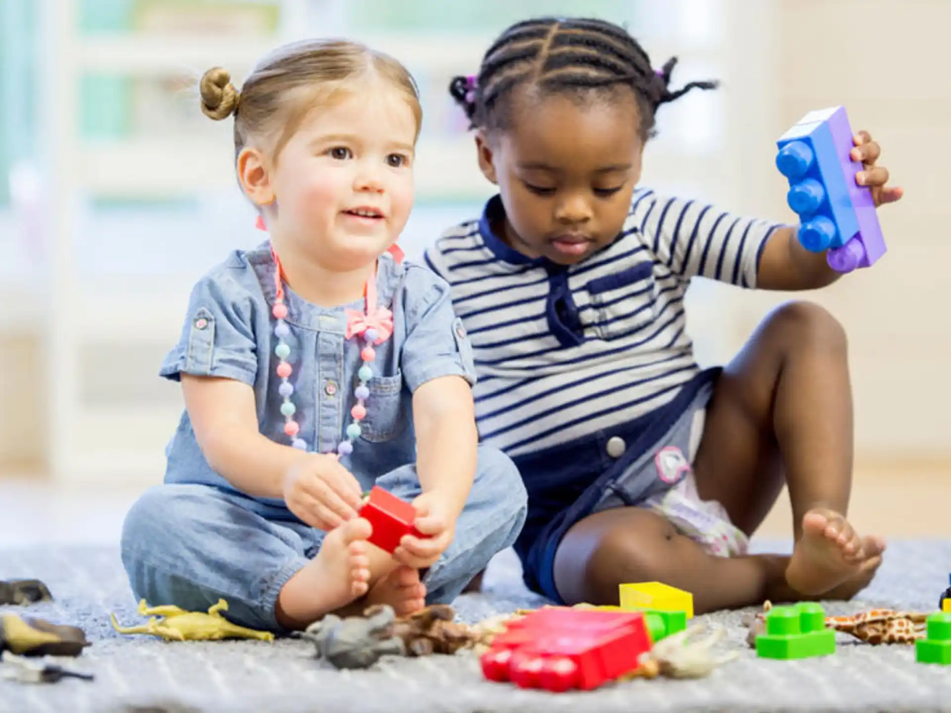 a couple of young children playing with toys on the floor