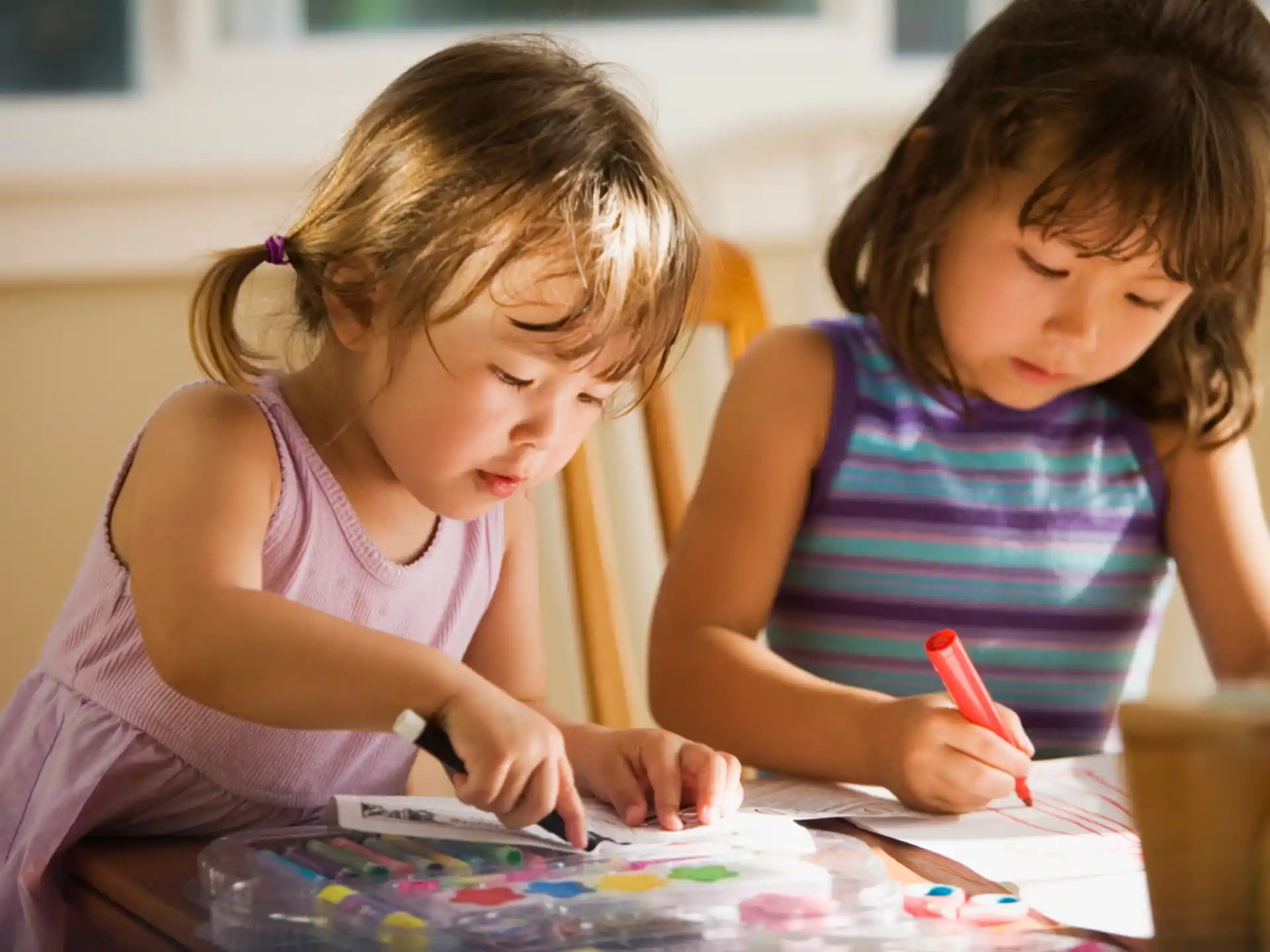 a young girl and a young girl coloring on a paper