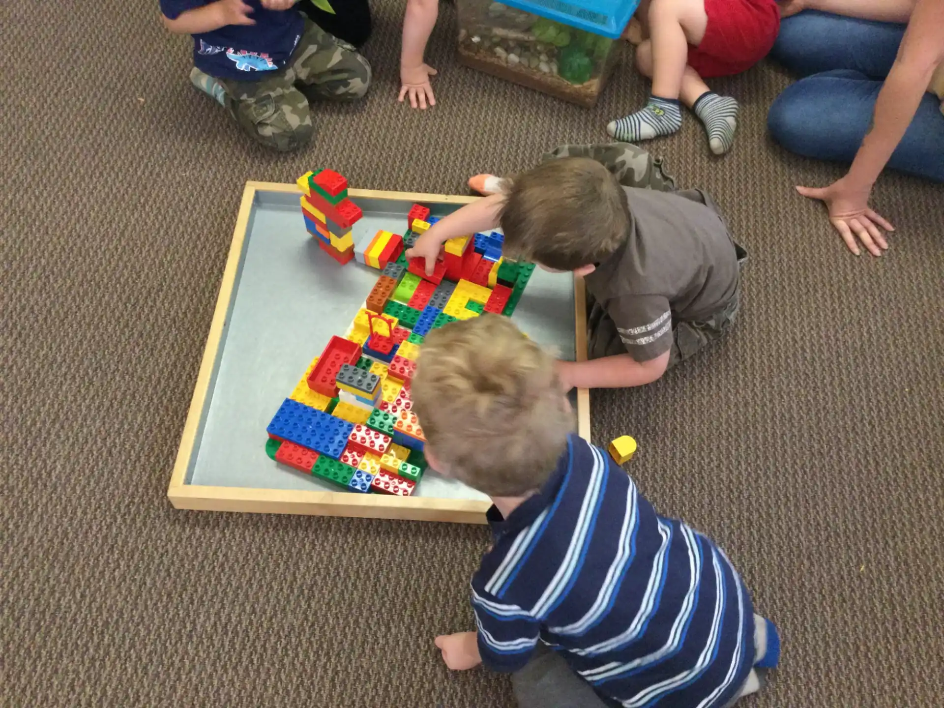 a couple of boys playing with a puzzle on the floor