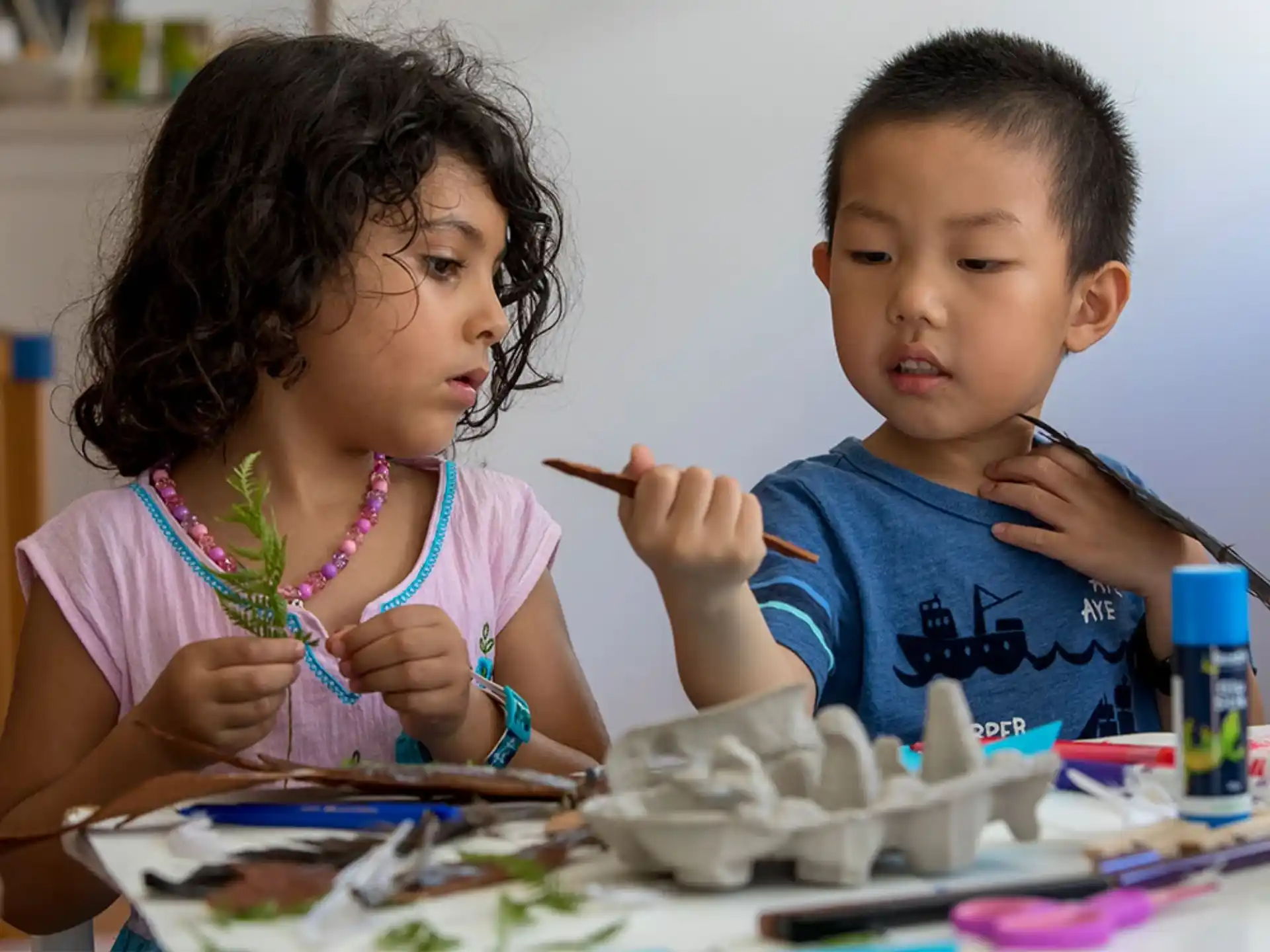 a couple of kids sitting at a table with food