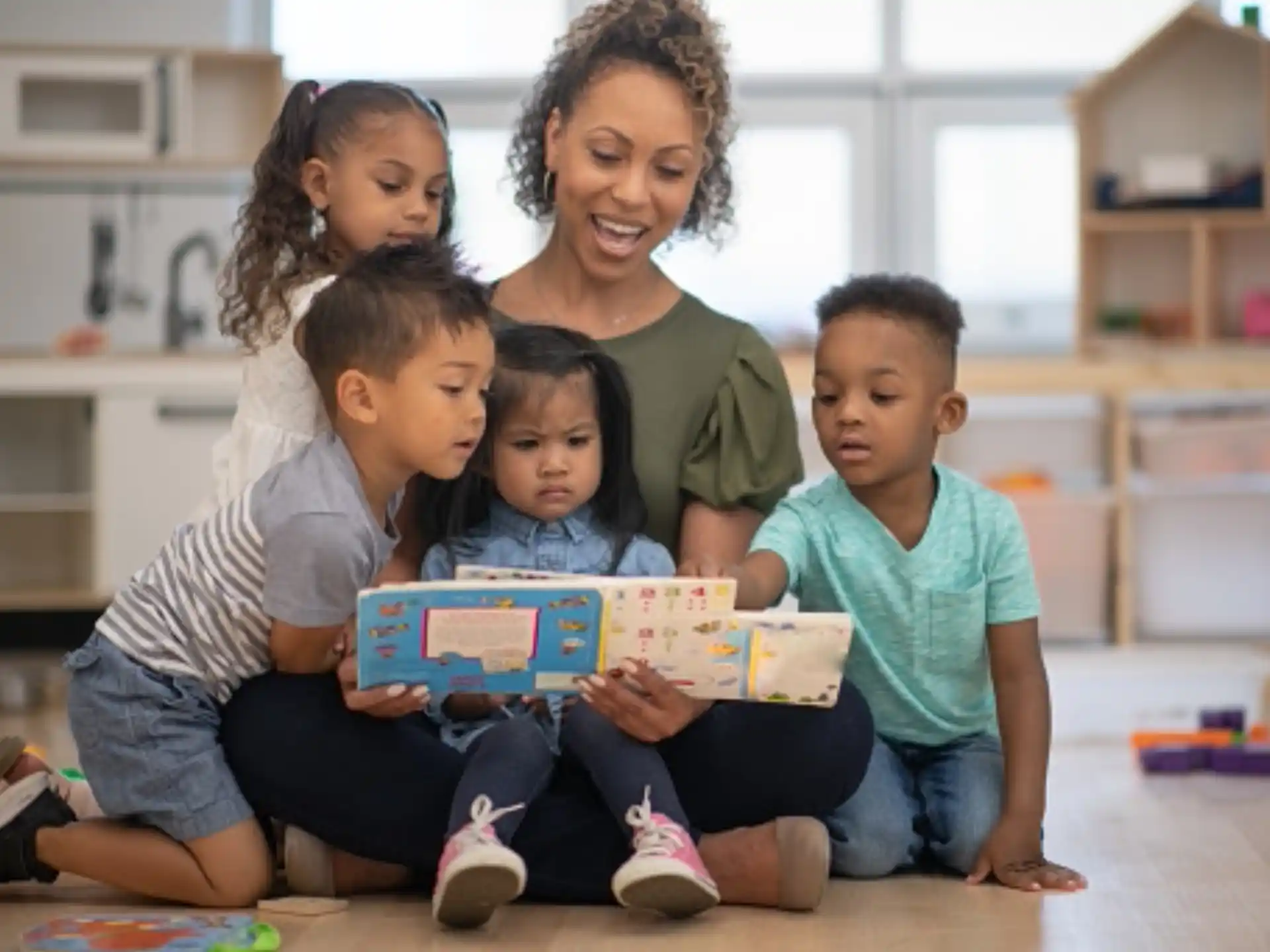 a person and several children sitting on the floor reading a book