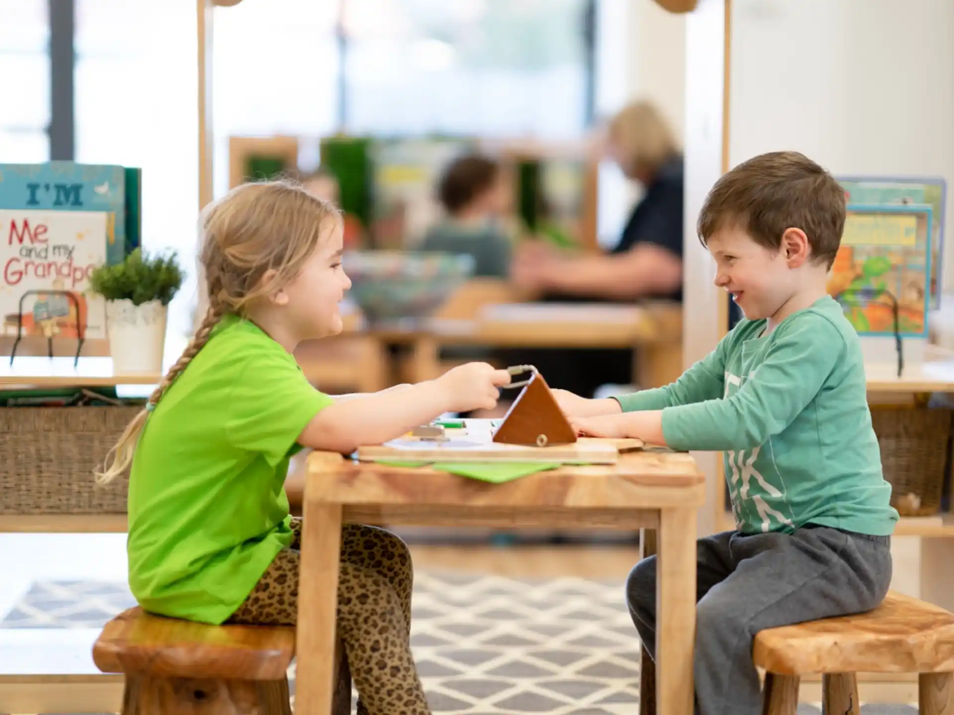 a boy and girl sitting at a table reading books