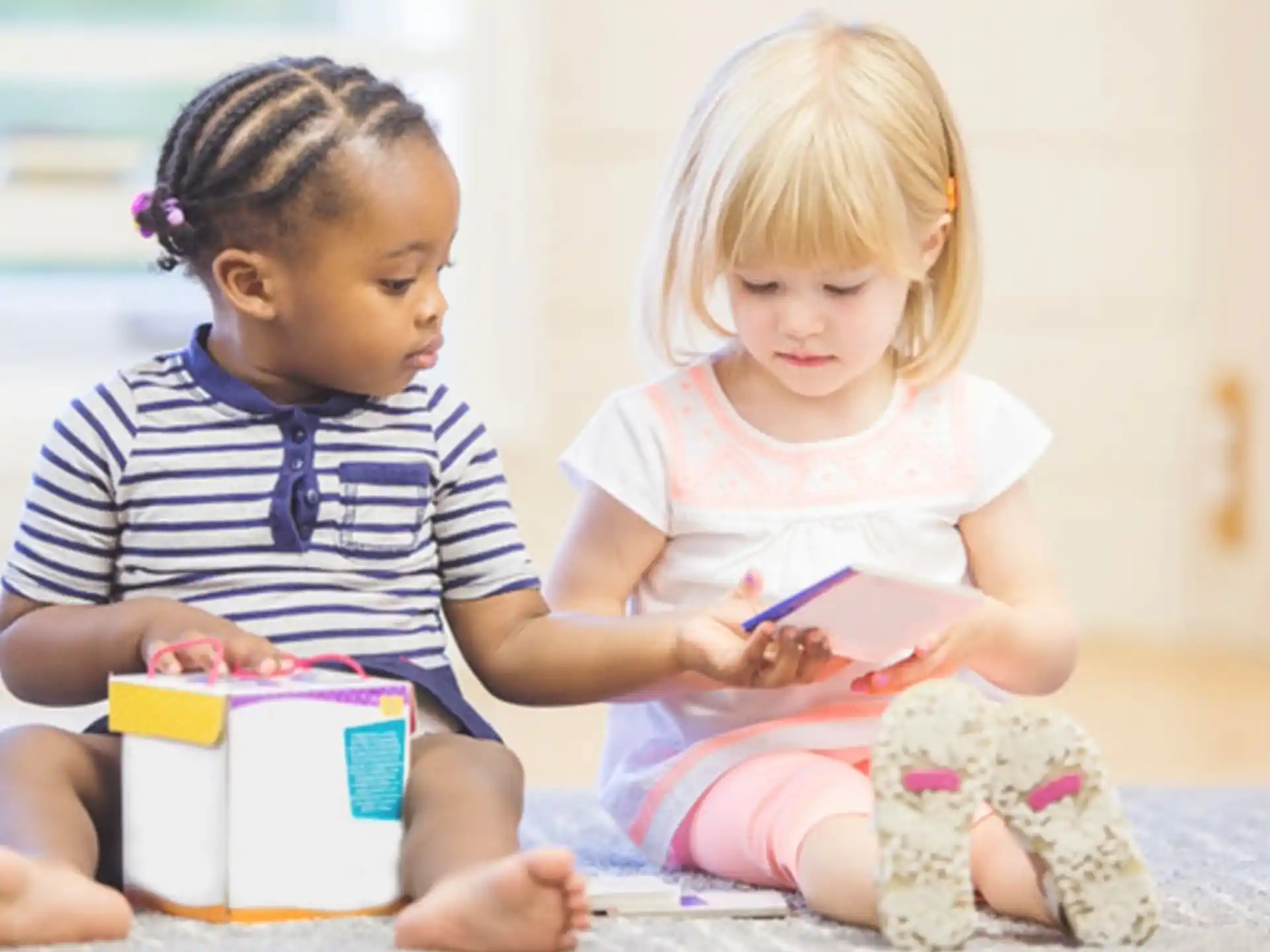 a couple of children sitting on the floor looking at a book