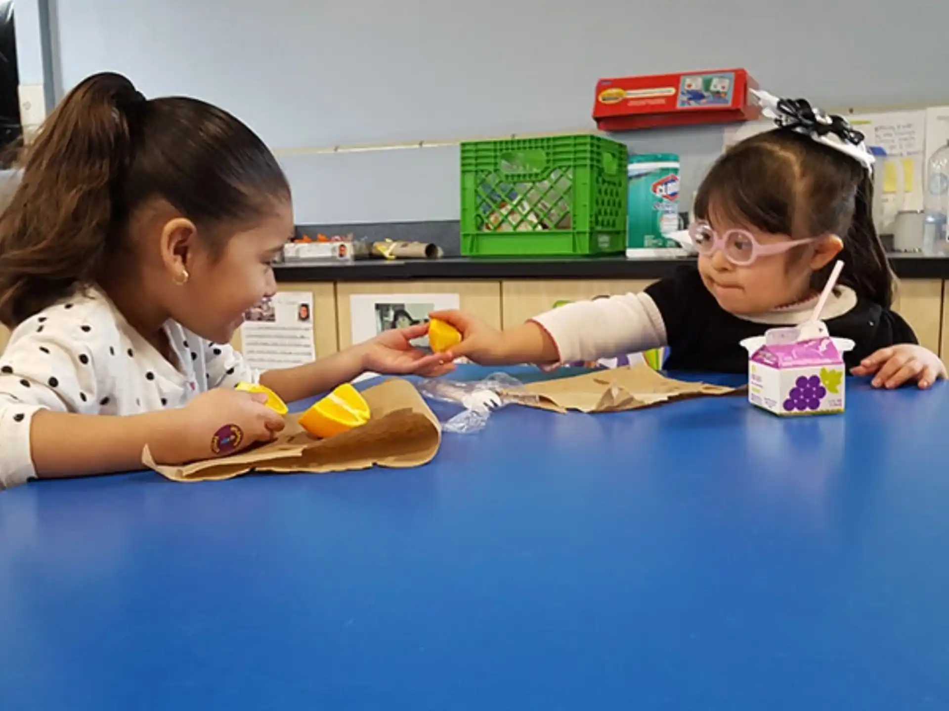 a couple of children sitting at a table with a blue table and a blue chair with a blue
