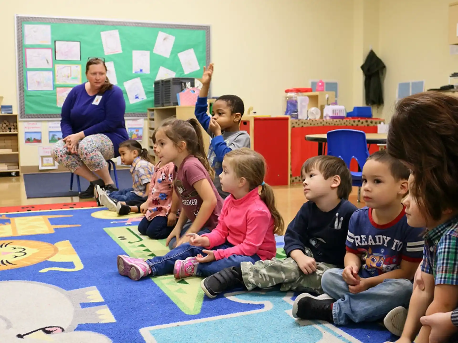 a group of children sitting on the floor in a classroom