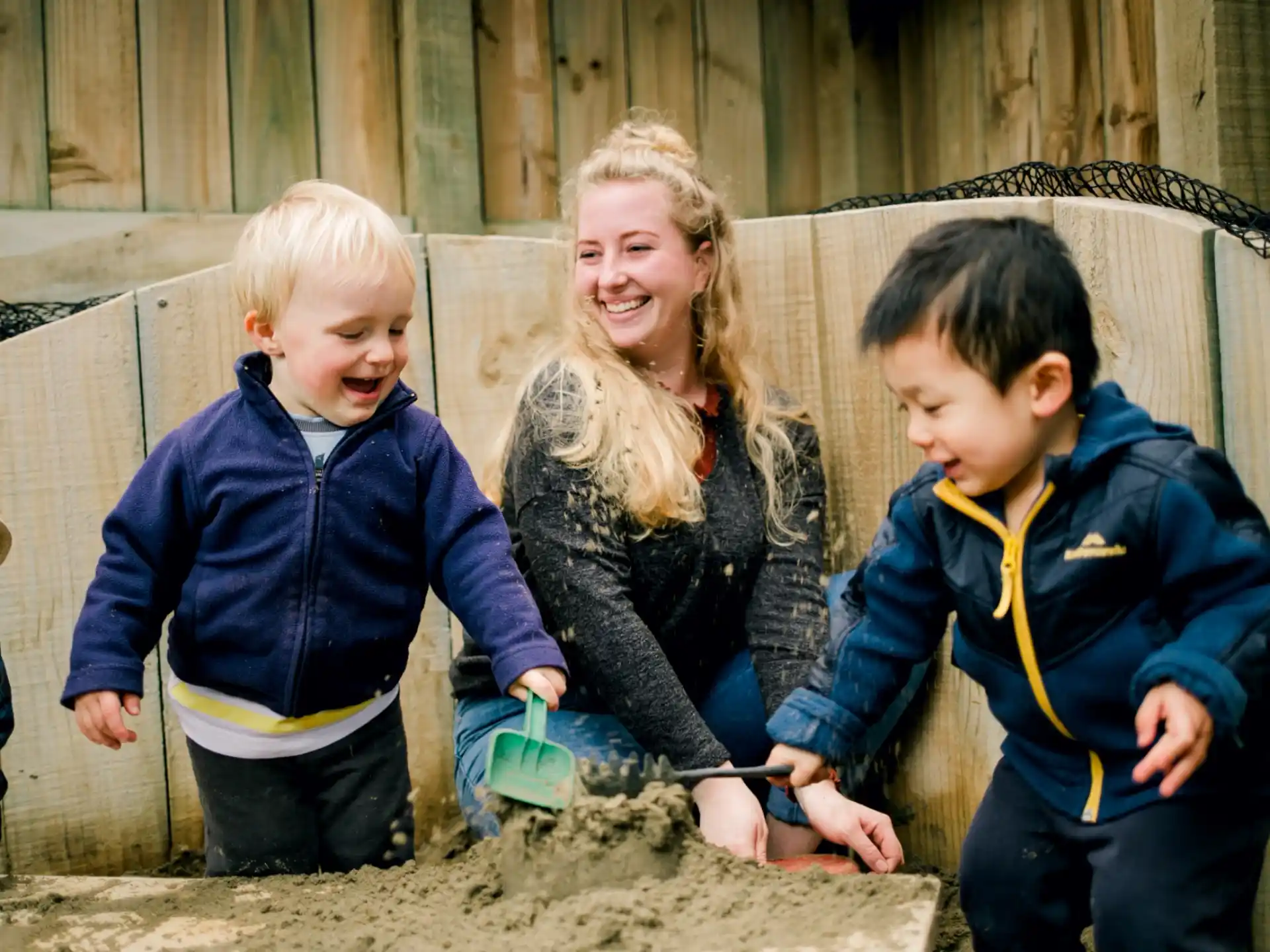 a person and two children playing in the sand