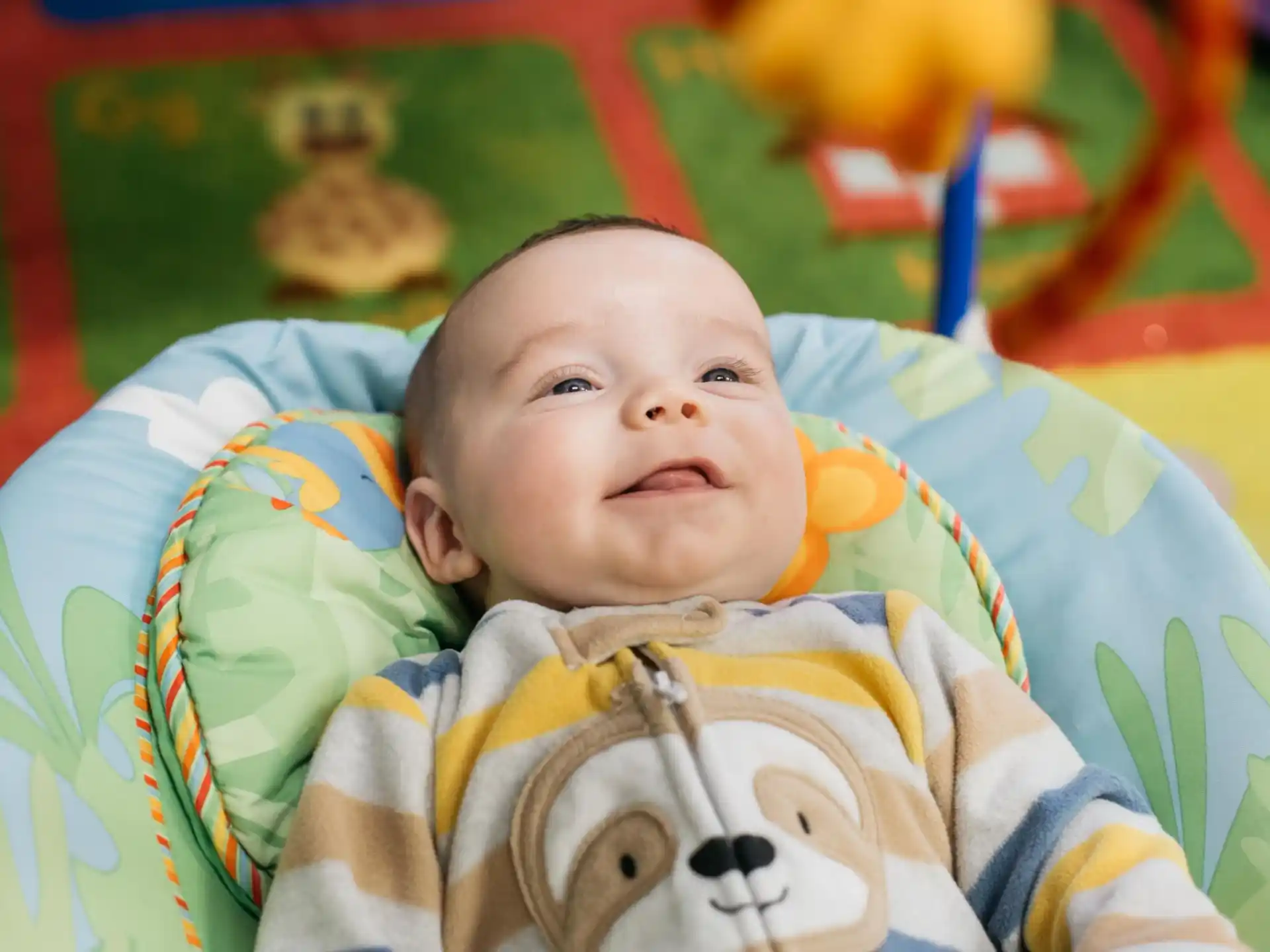 a baby lying on a colorful blanket