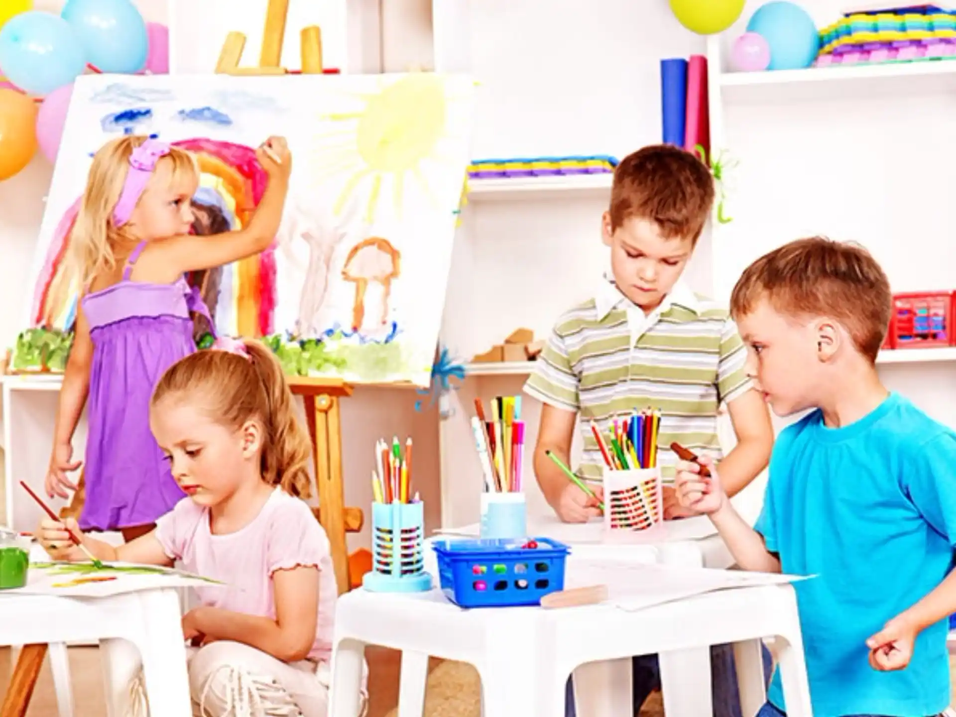 a group of children sitting around a table with balloons