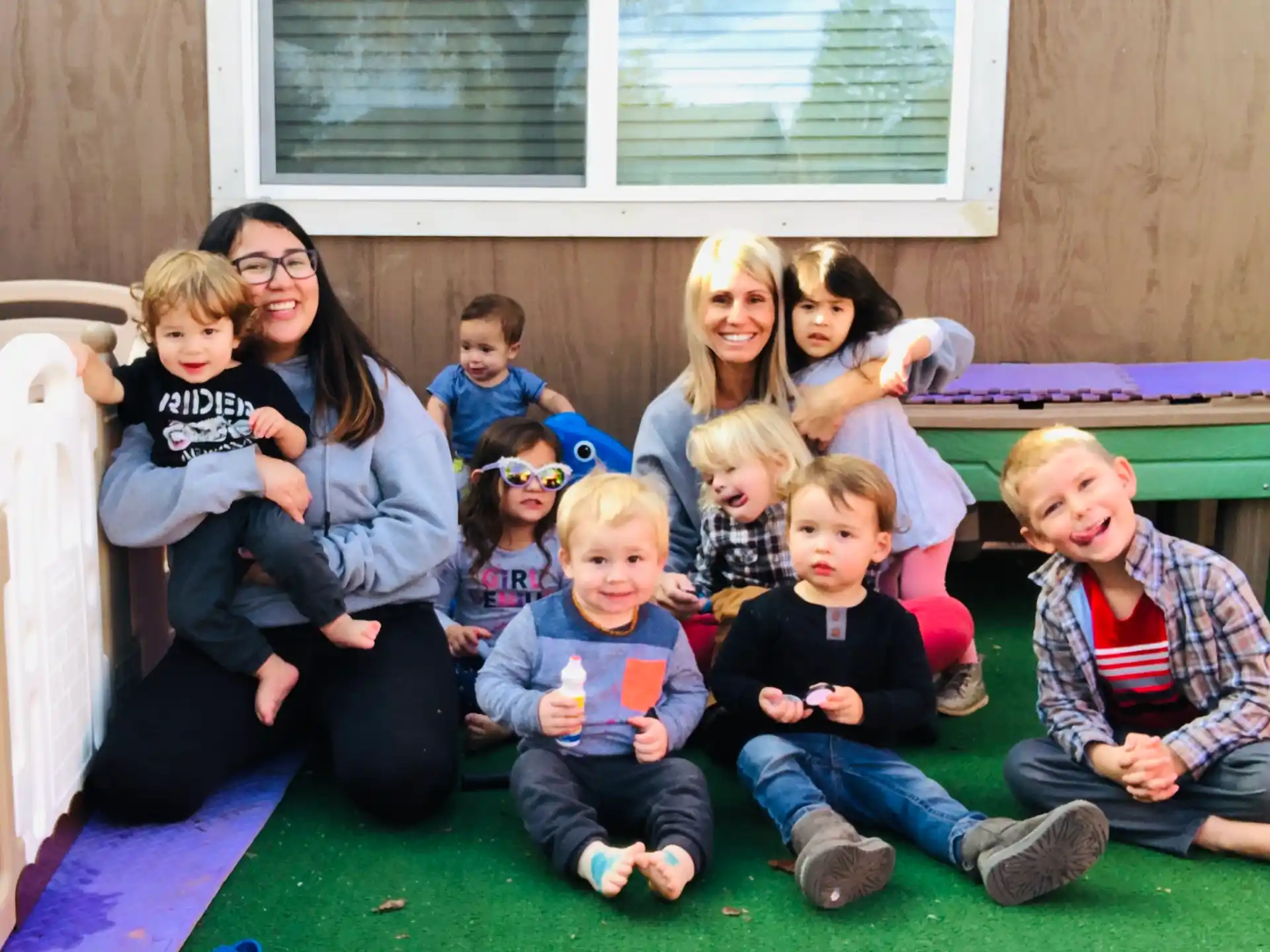 a group of children sitting on the ground posing for a photo