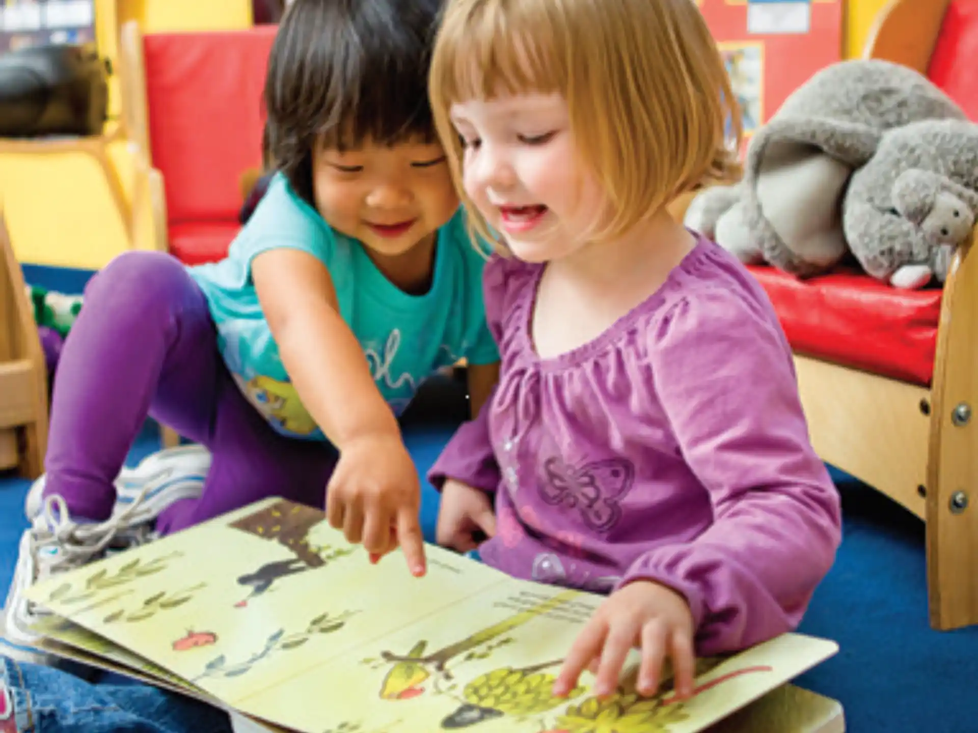 a couple of children sitting at a table looking at a book