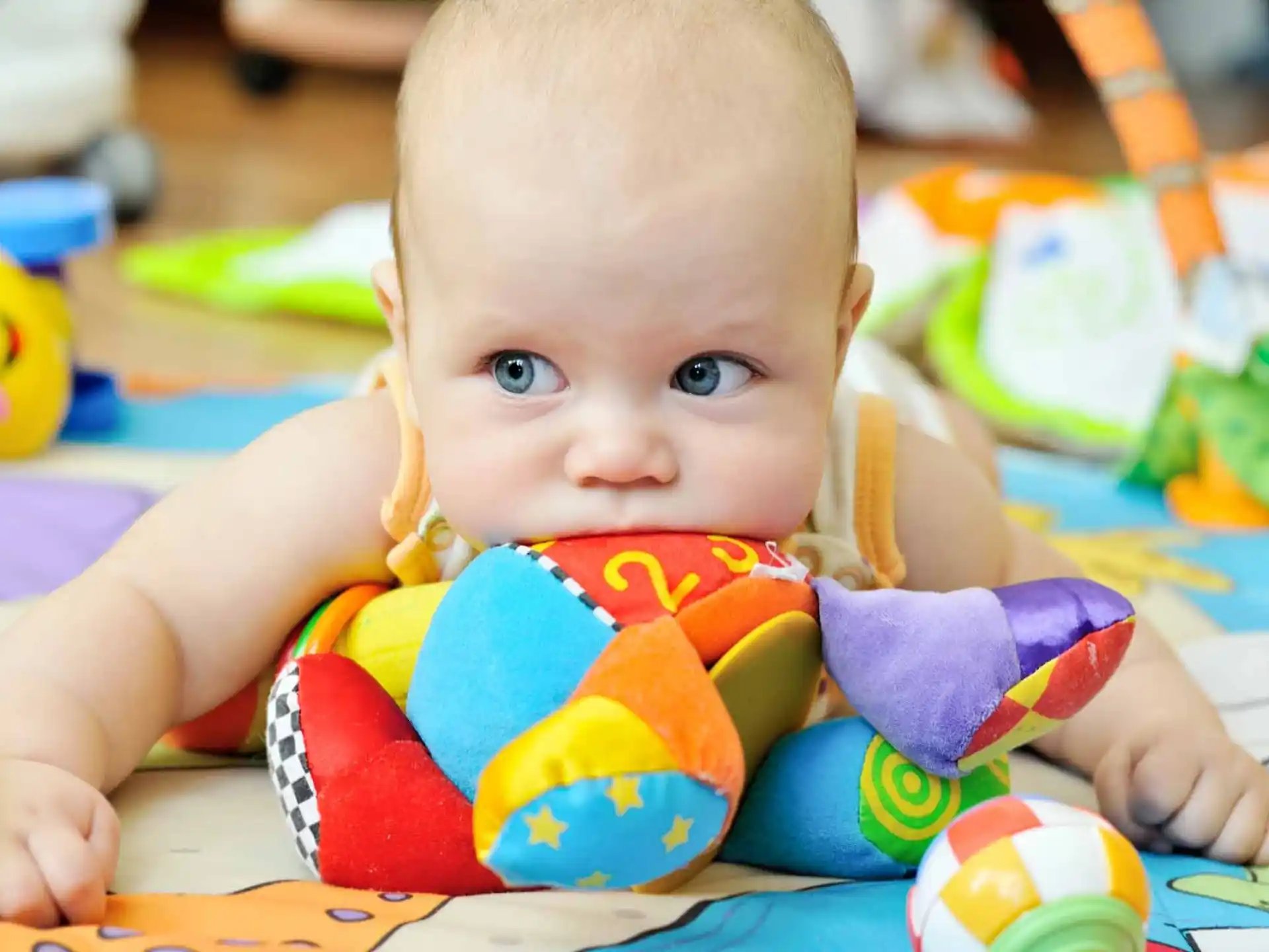 a baby lying on a colorful blanket