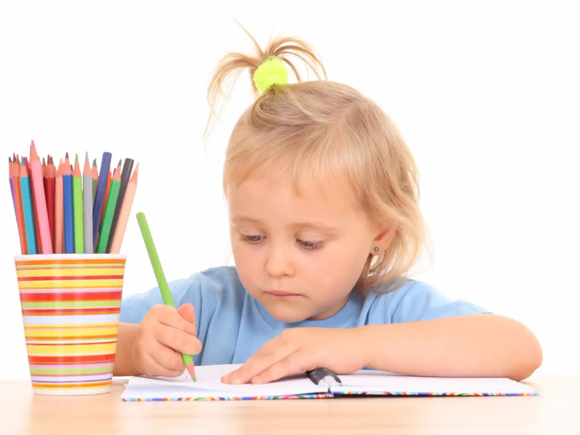 a child sitting at a table with colored pencils
