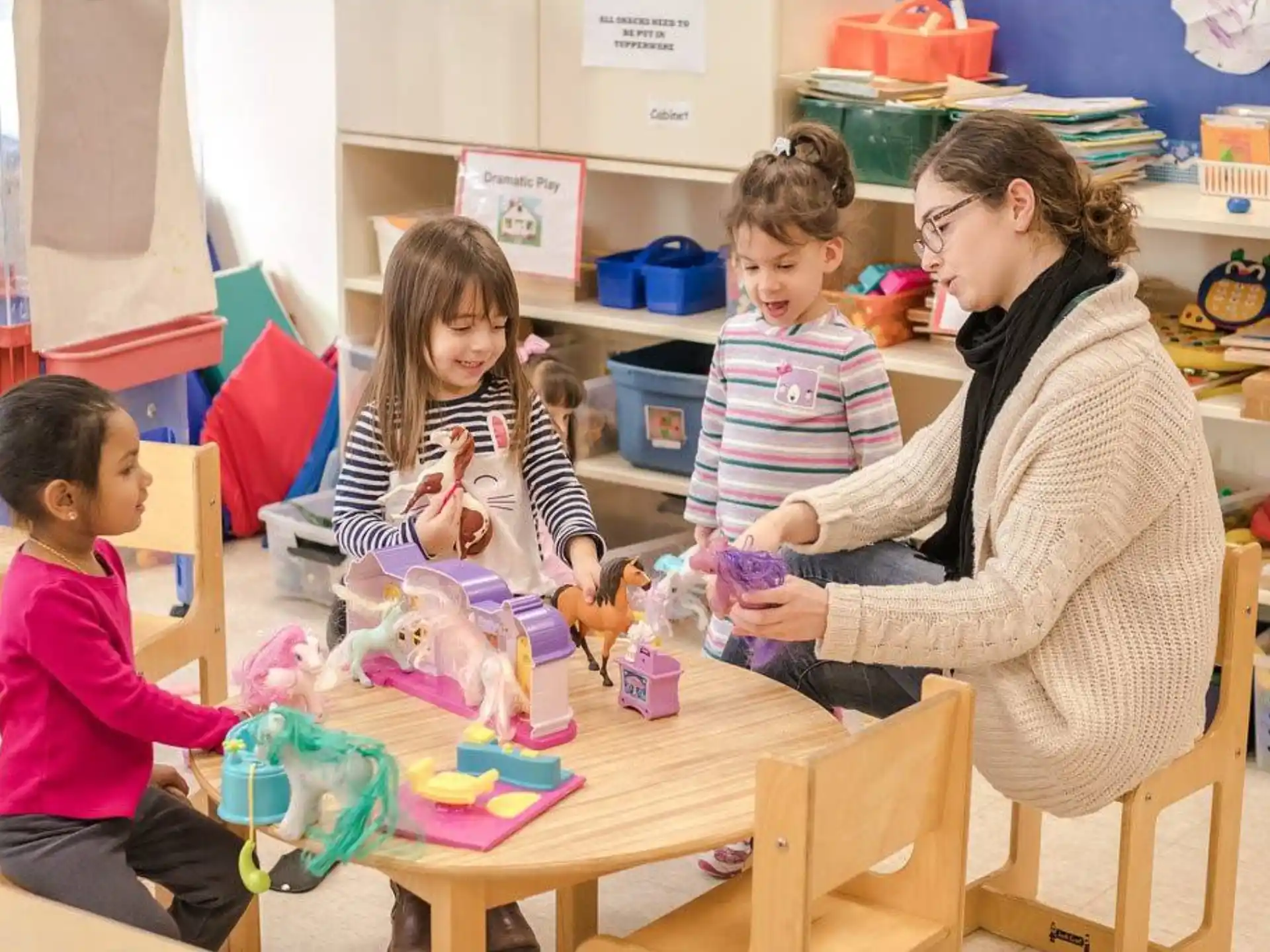 a person and children sitting at a table with toys