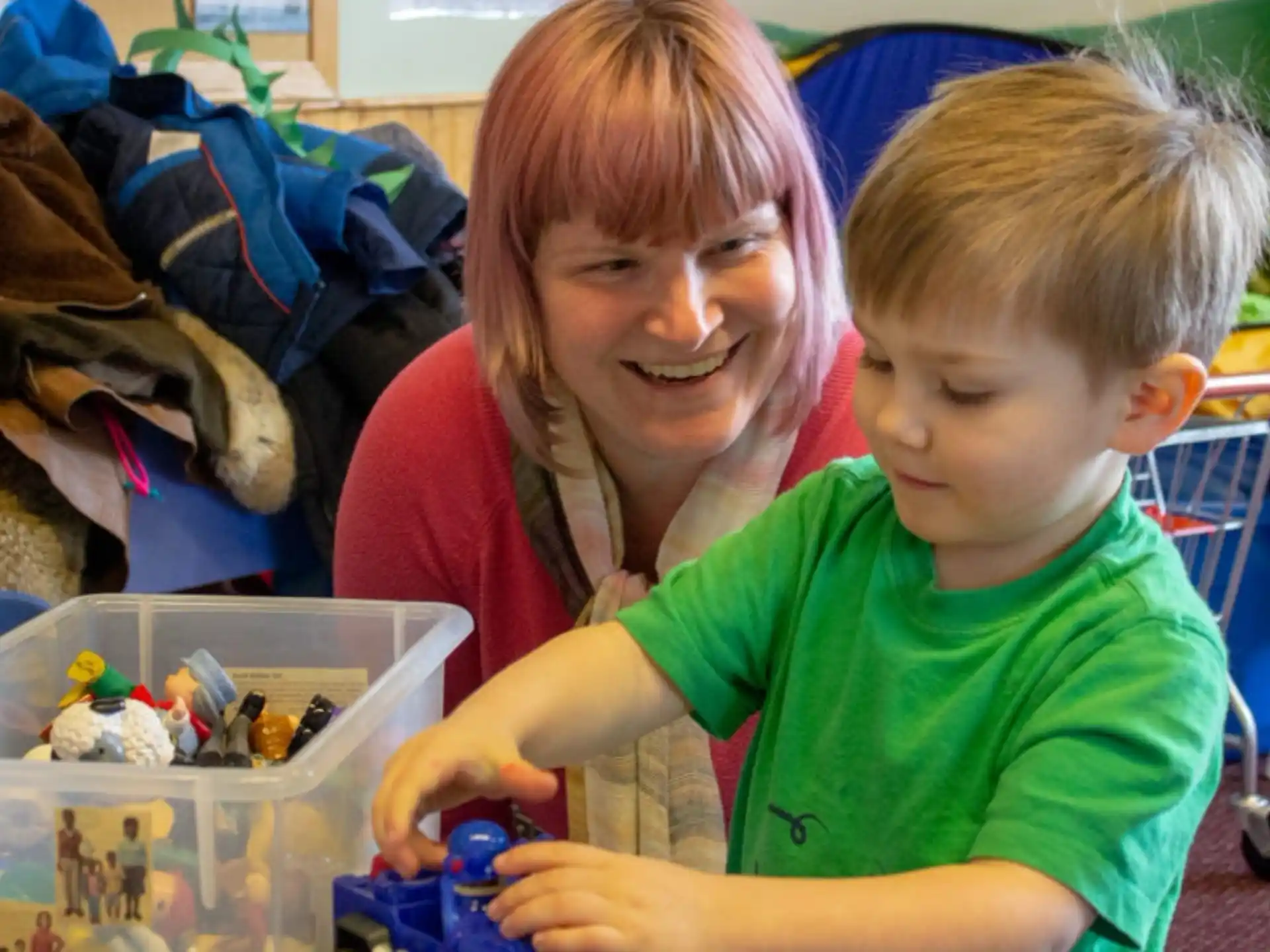 a person and a boy playing with toys in a room