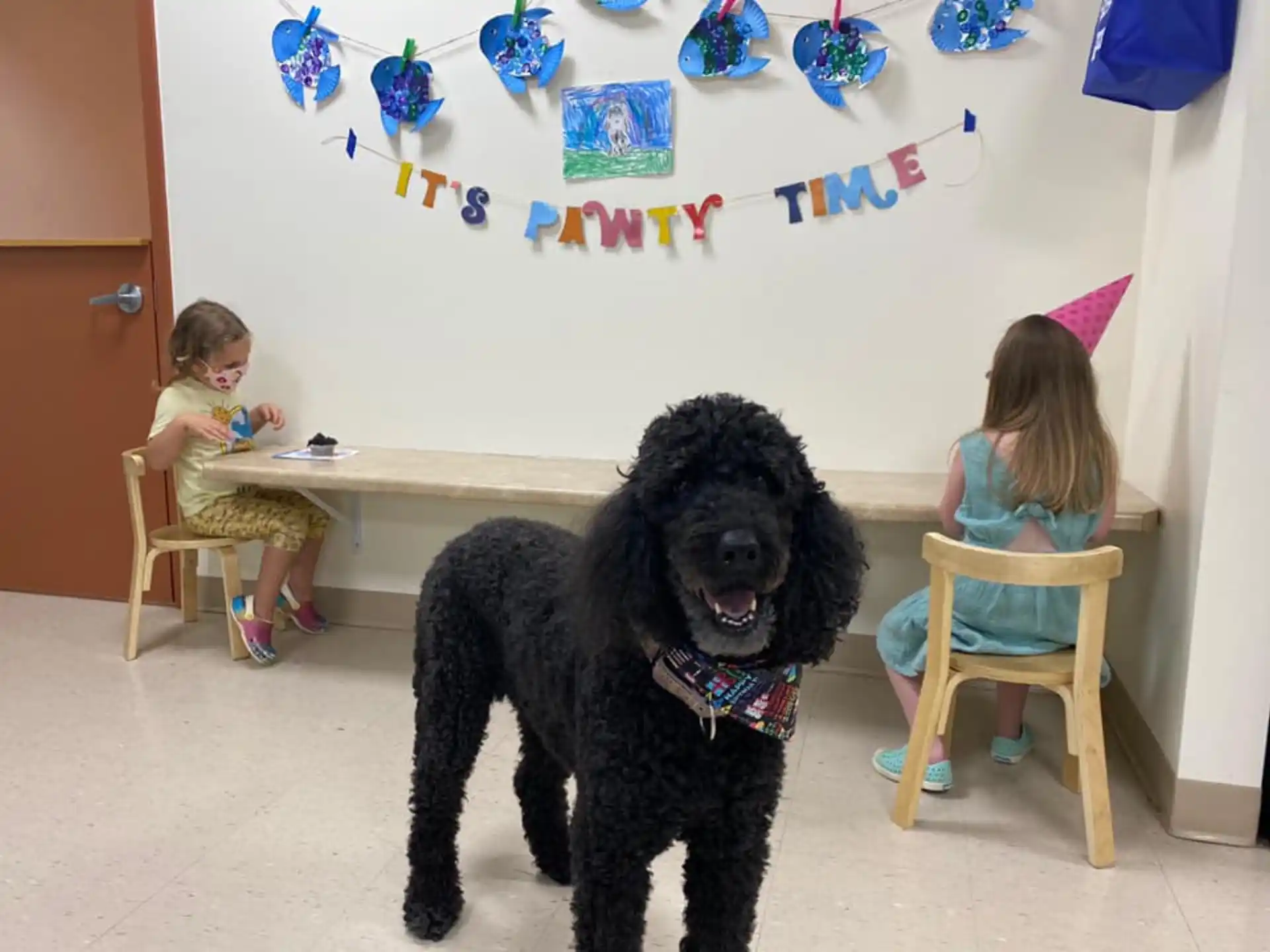 a dog and a girl sitting in a room with a table and chairs