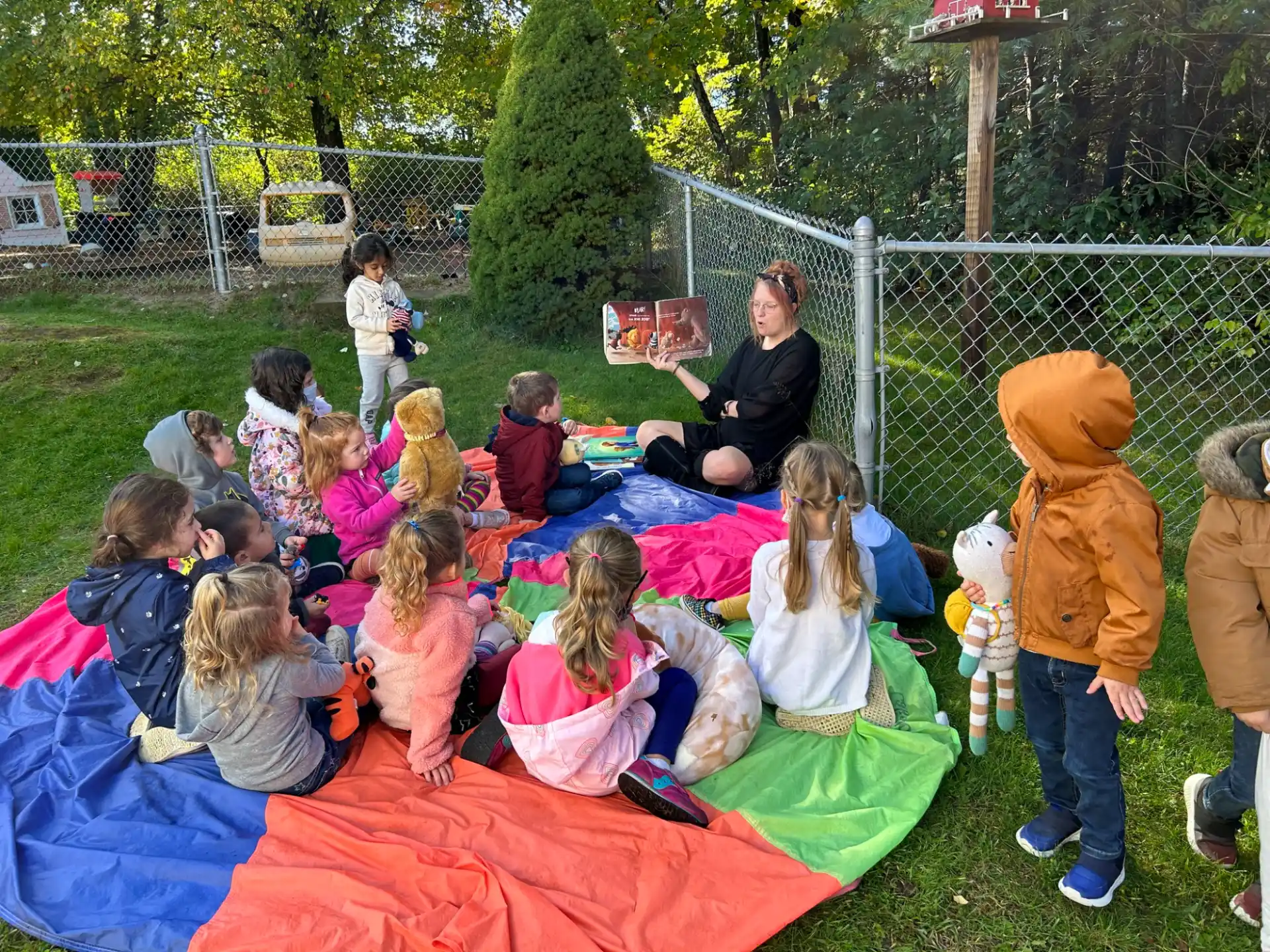a group of children sitting on a blanket in a grassy area
