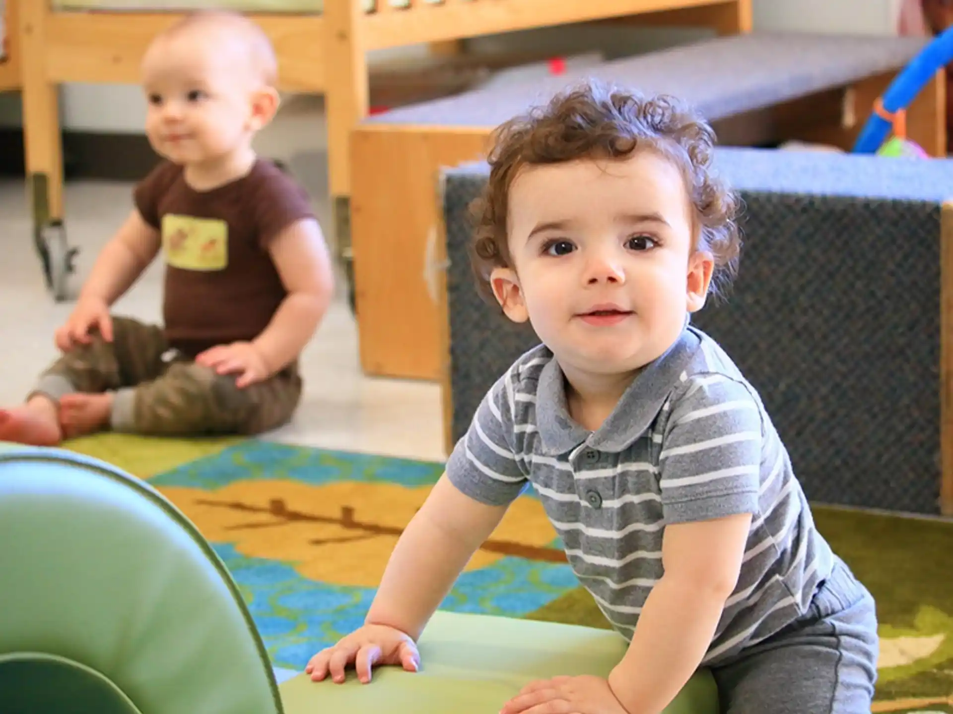 a couple of babies sitting on a green mat