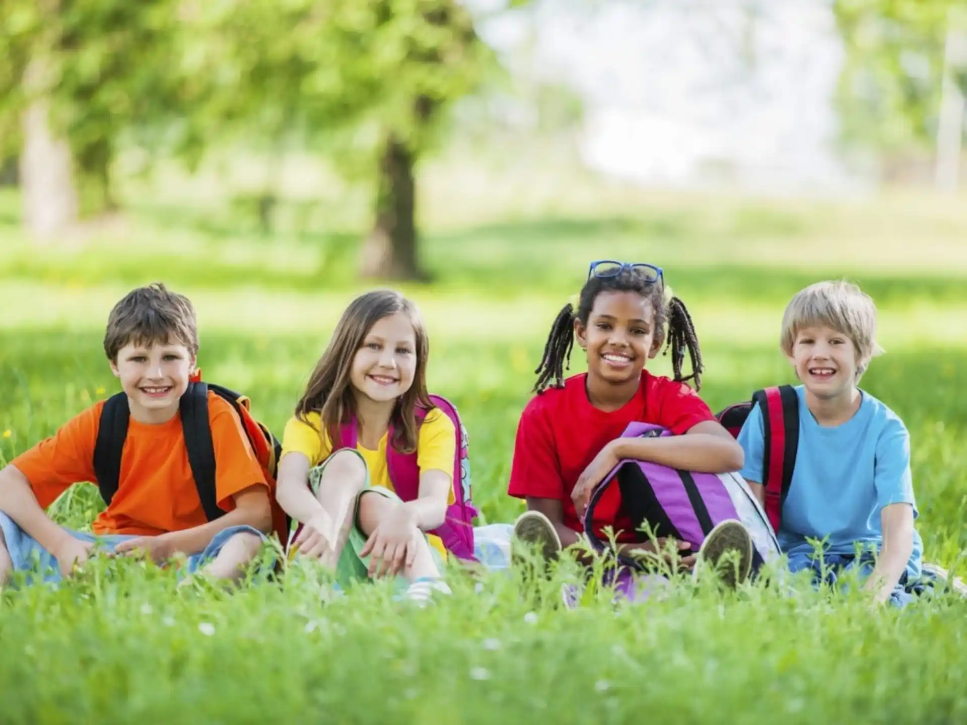 a group of children sitting in the grass