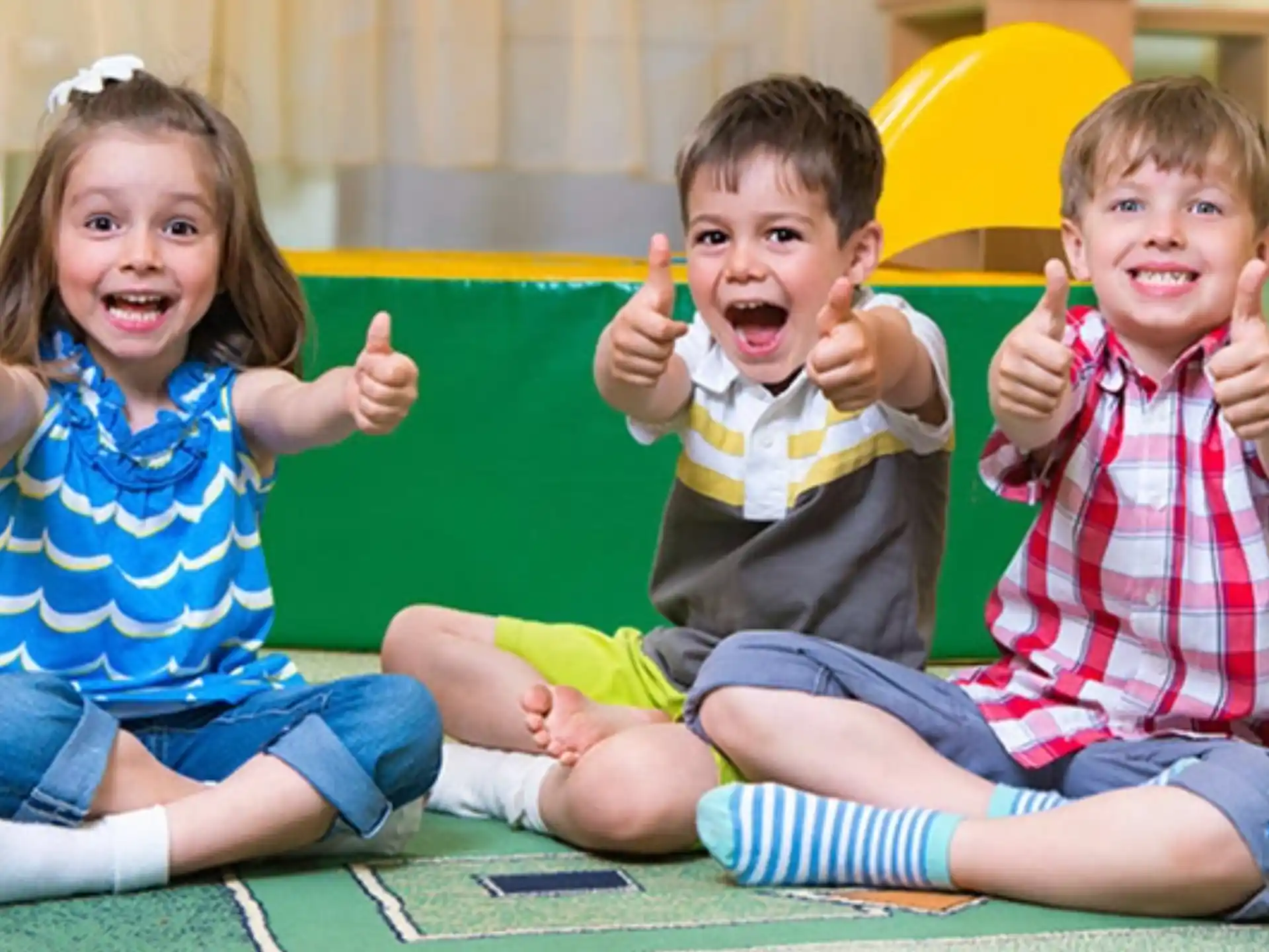 a group of children sitting on the ground with their hands up