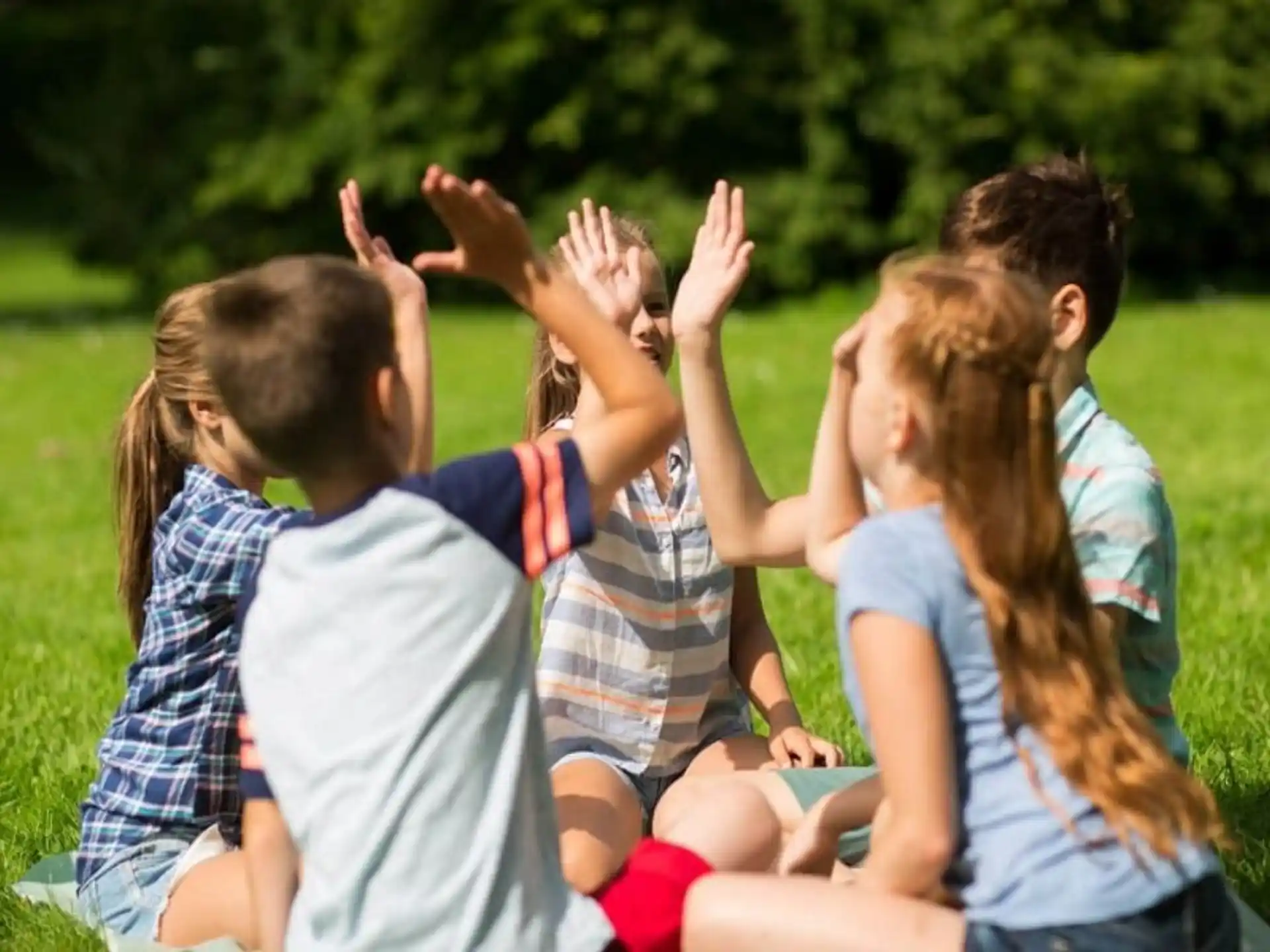 a group of people sitting in a circle with their hands up