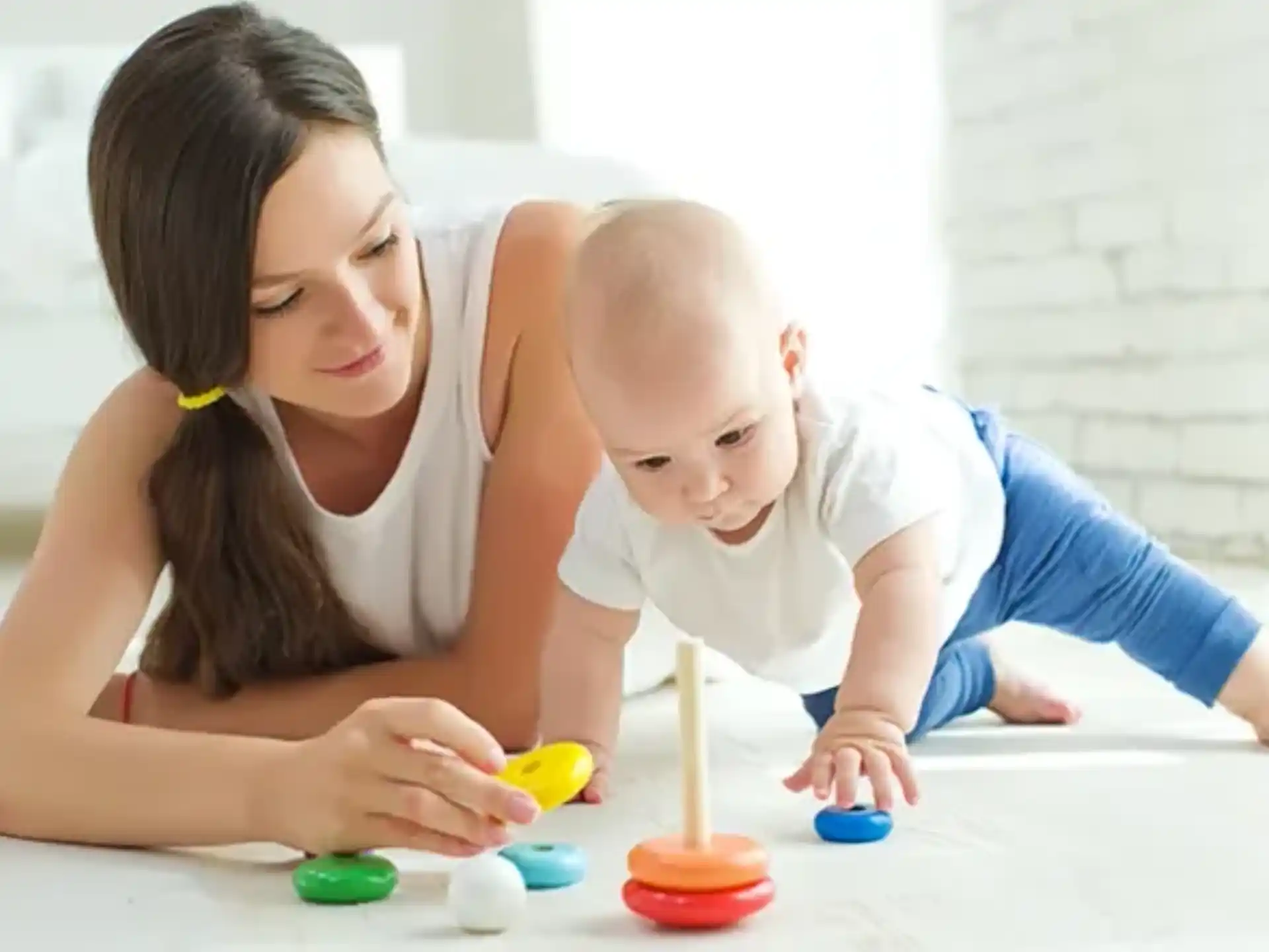a person and a baby playing with toys on the floor