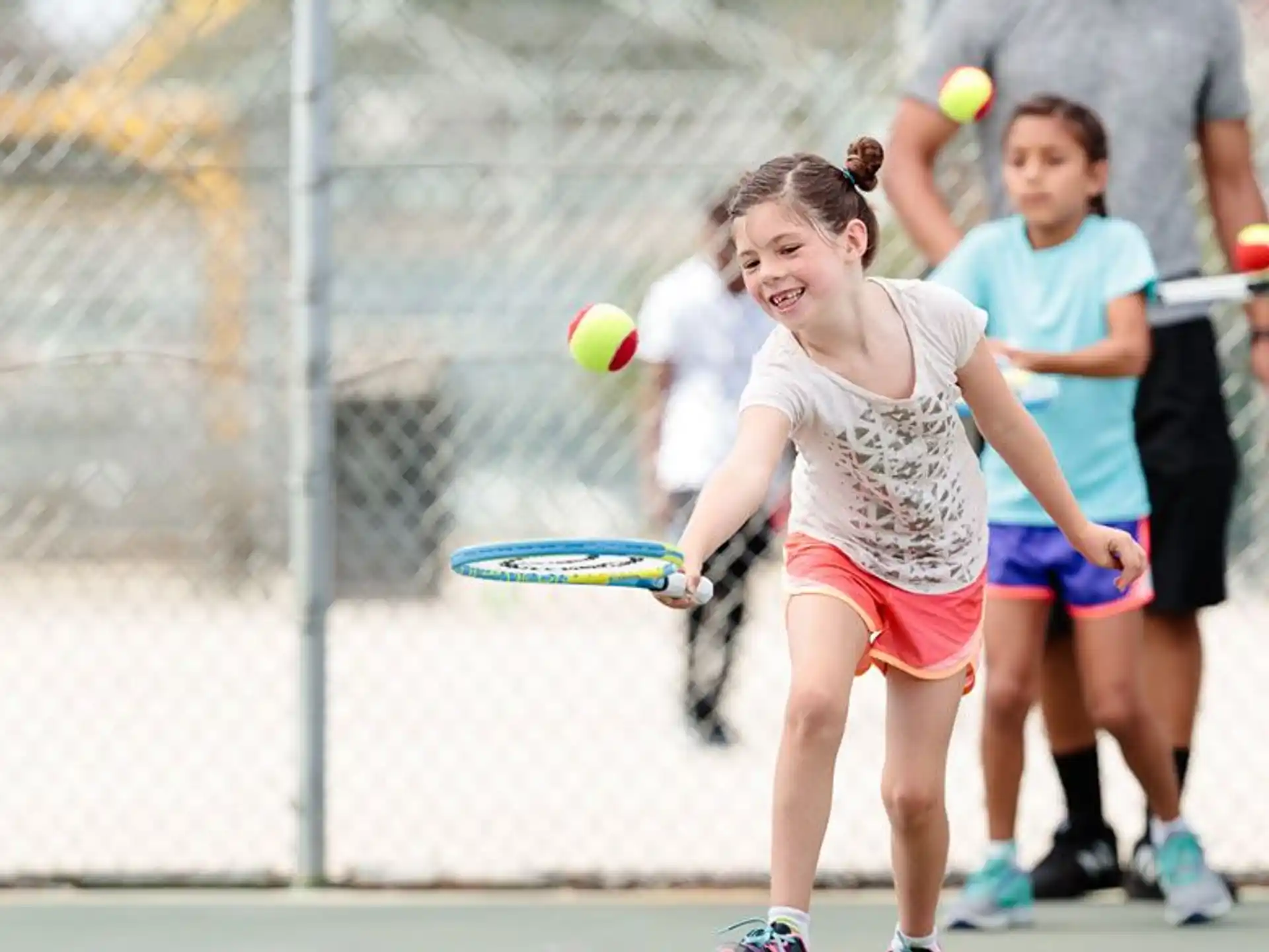 a girl hitting a ball with a tennis racket
