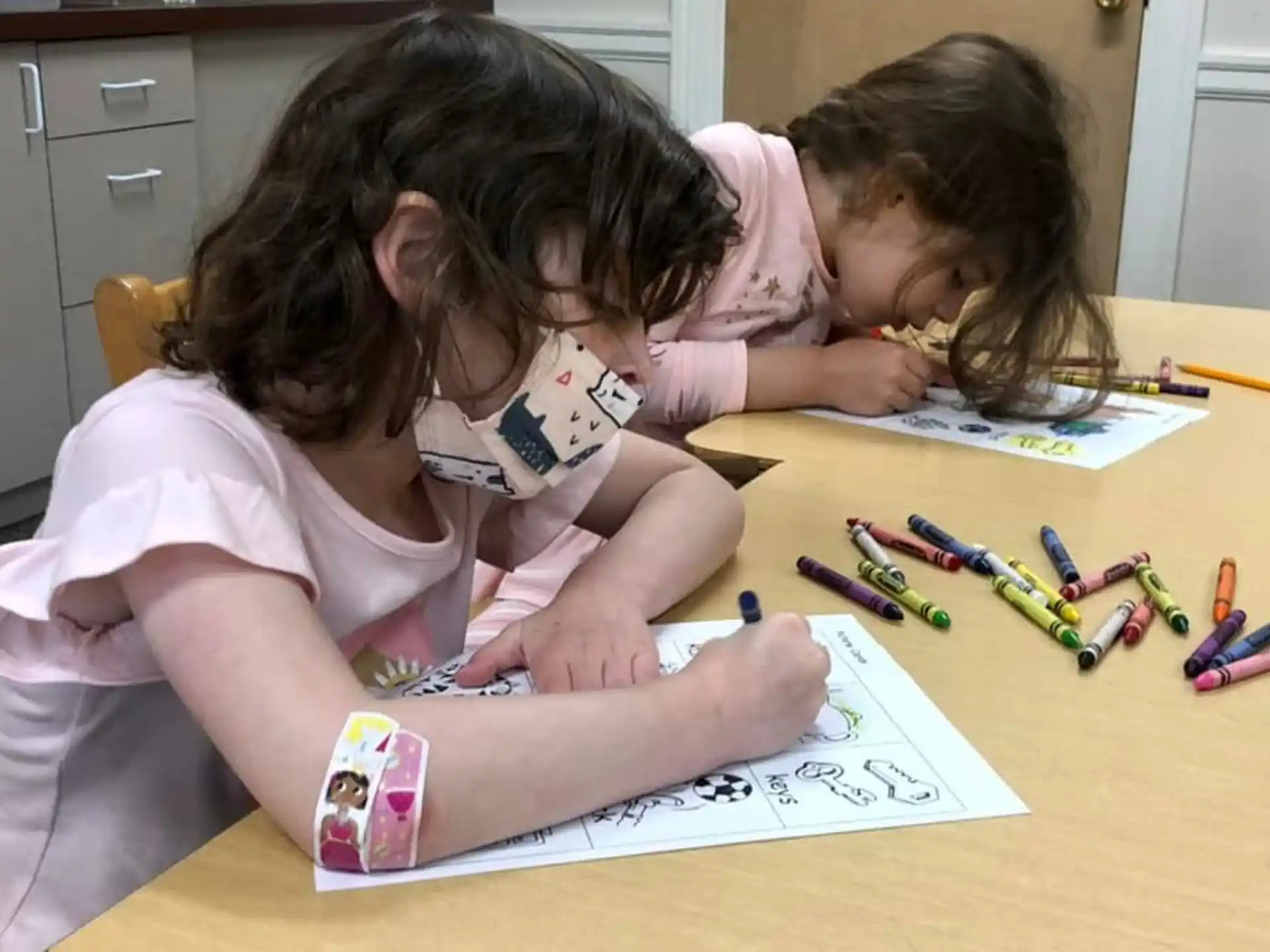 a few young girls coloring on paper