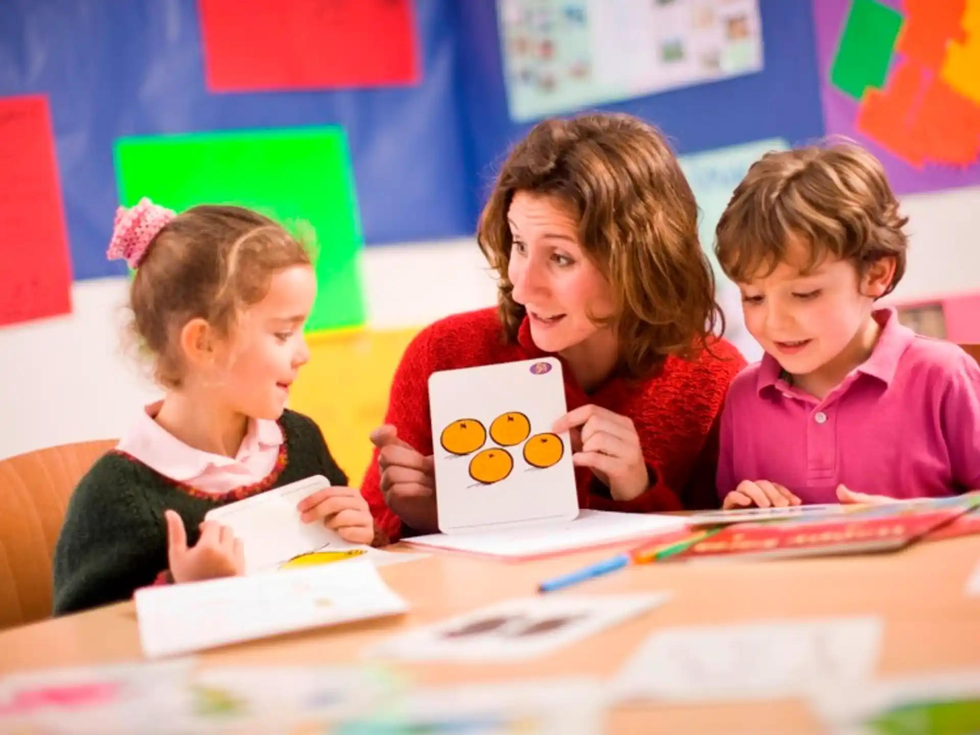 a group of children sitting at a table looking at a paper