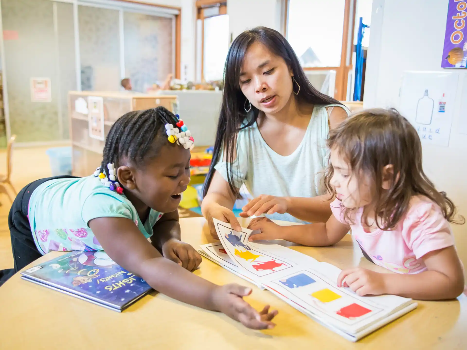 a group of children sitting at a table looking at a book