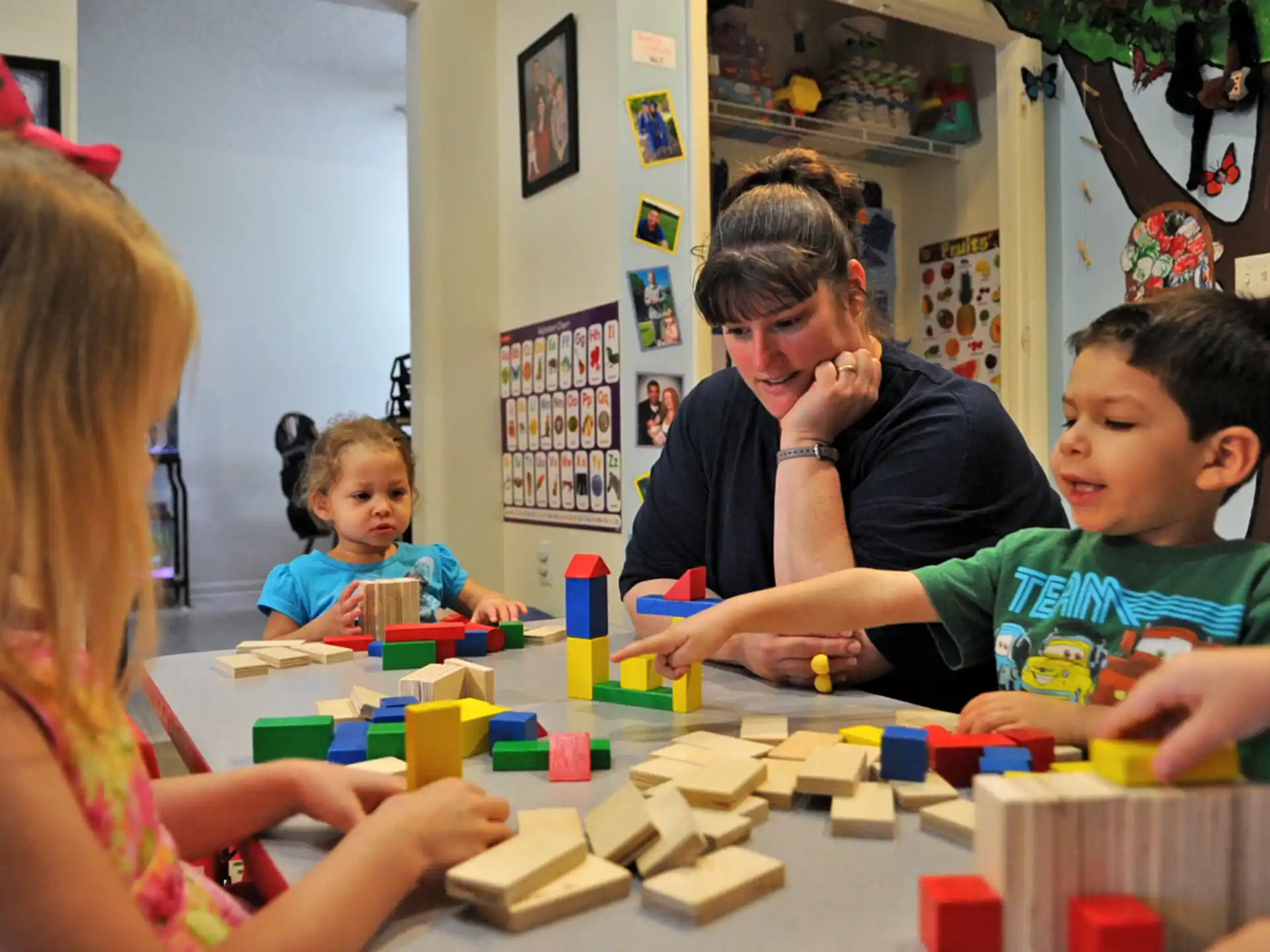 a person and a couple of children playing with building blocks