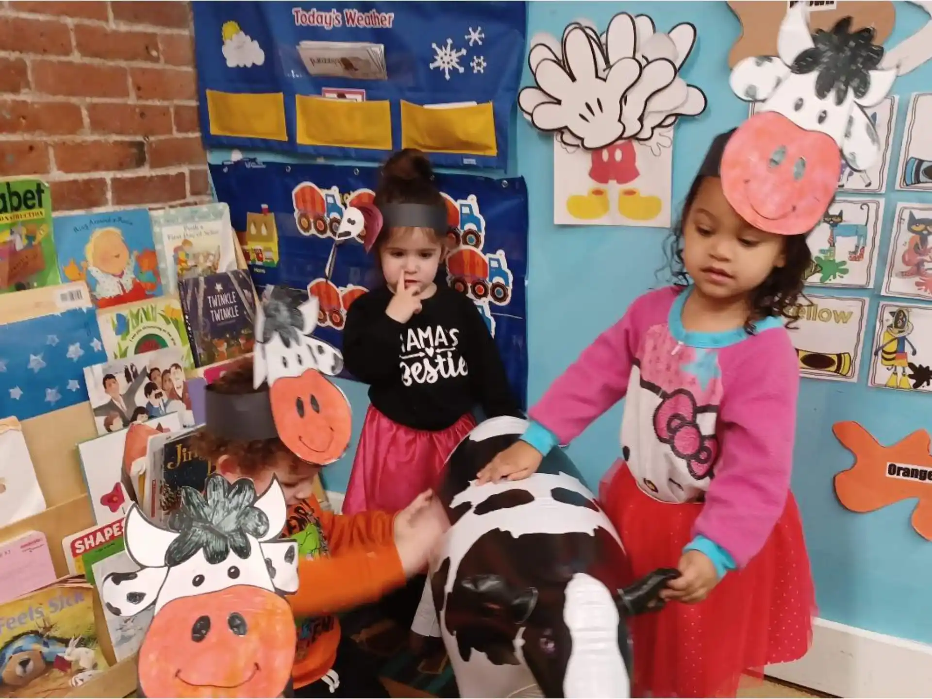 a couple of kids on a toy horse in a room with posters
