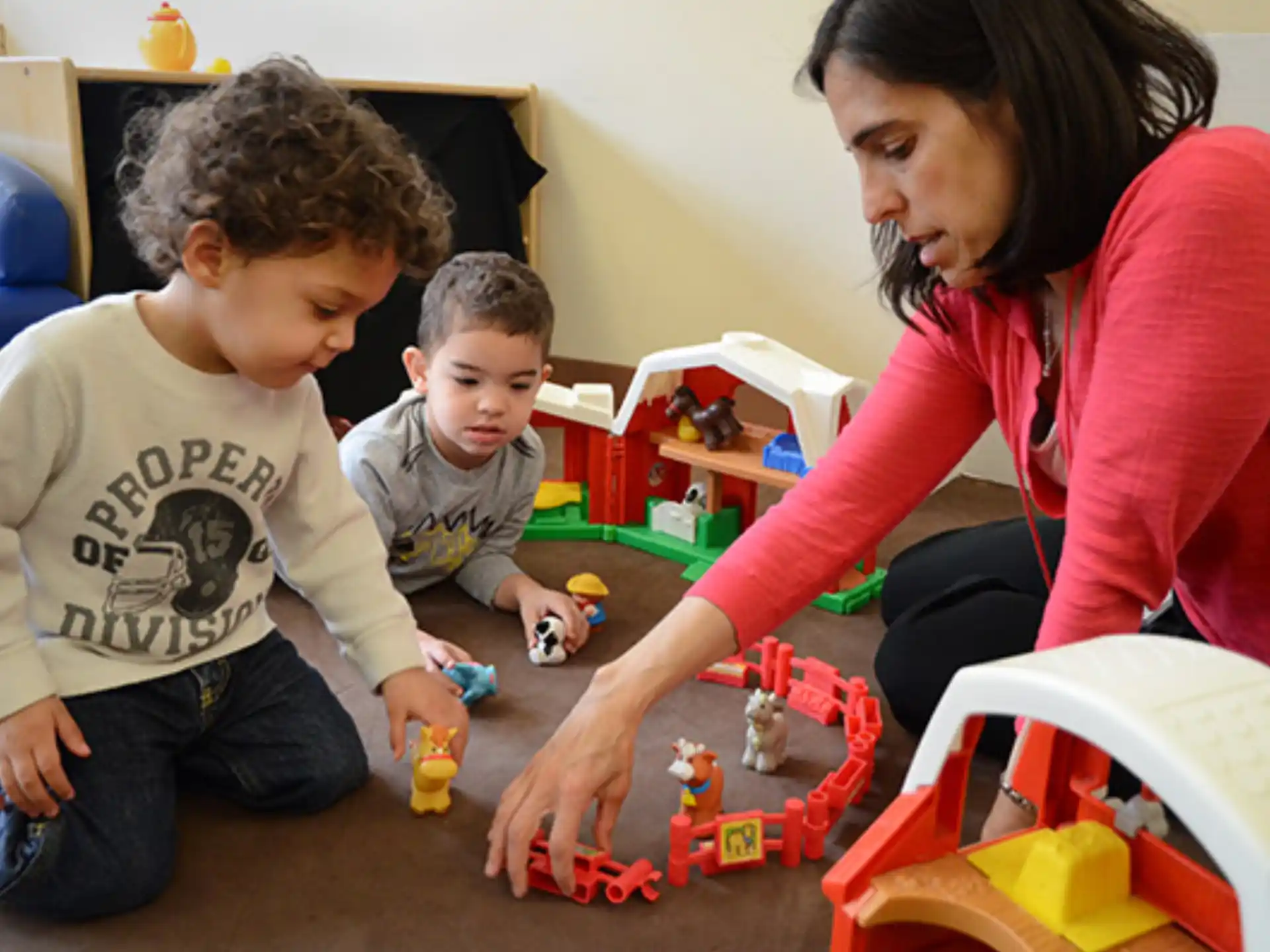 a person and two boys playing with toys on the floor