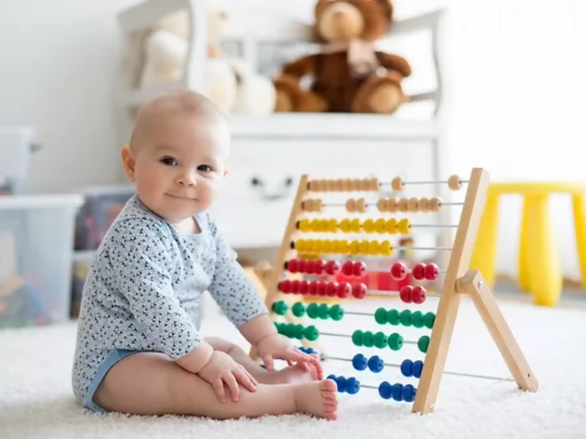 a baby sitting on the floor next to a toy house