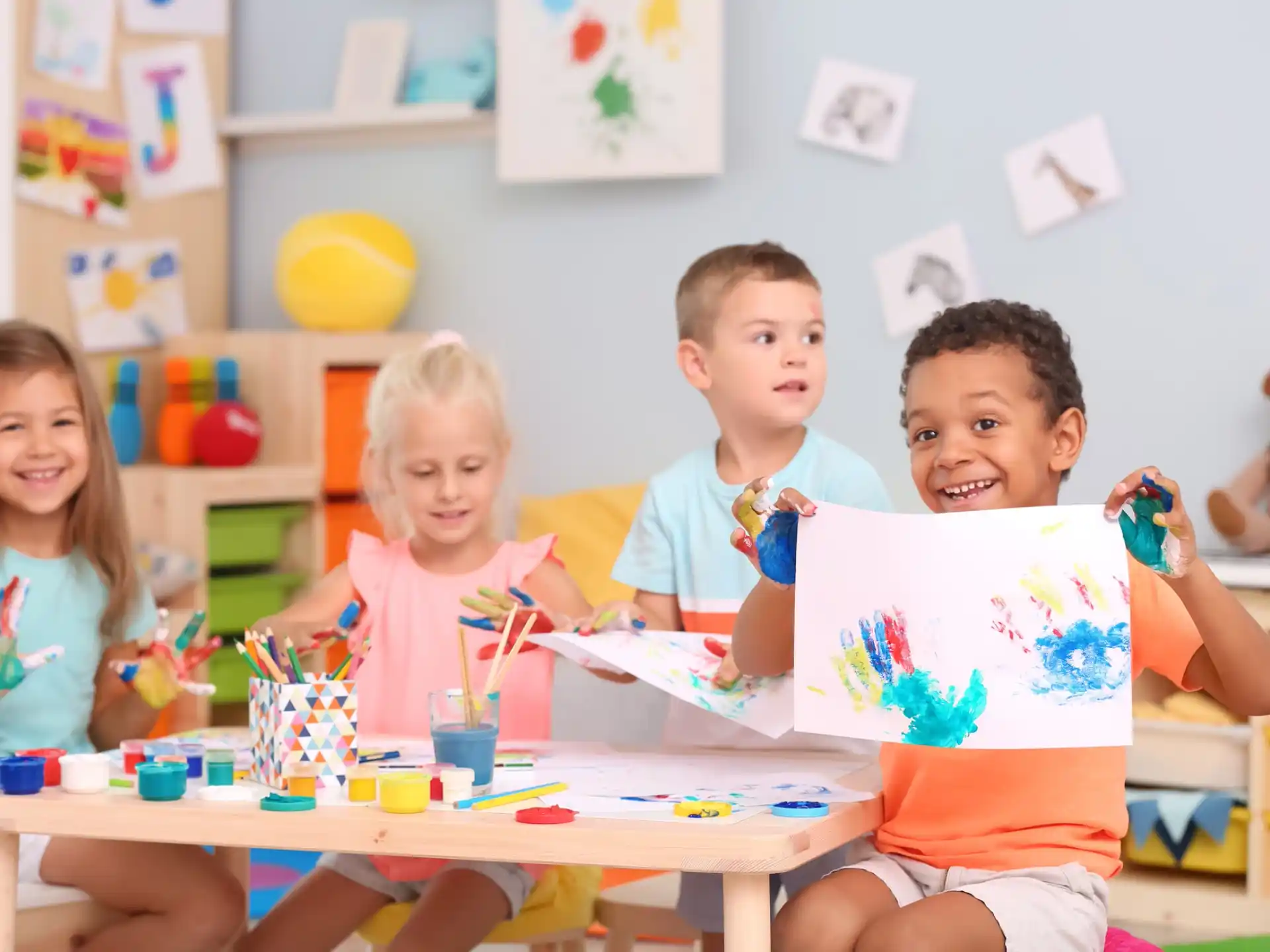 a group of children sitting at a table with a paper and pencils