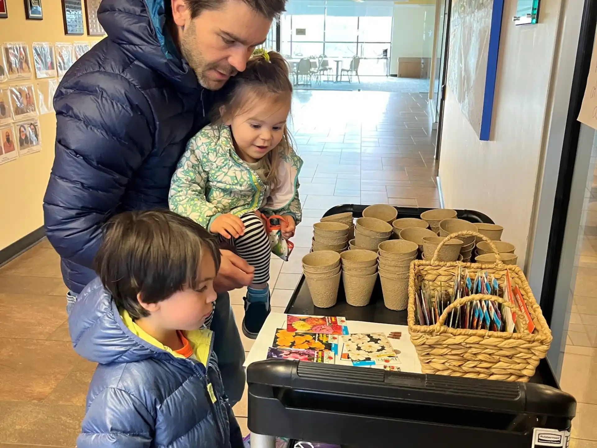 a man and two children standing next to a table with baskets of bread