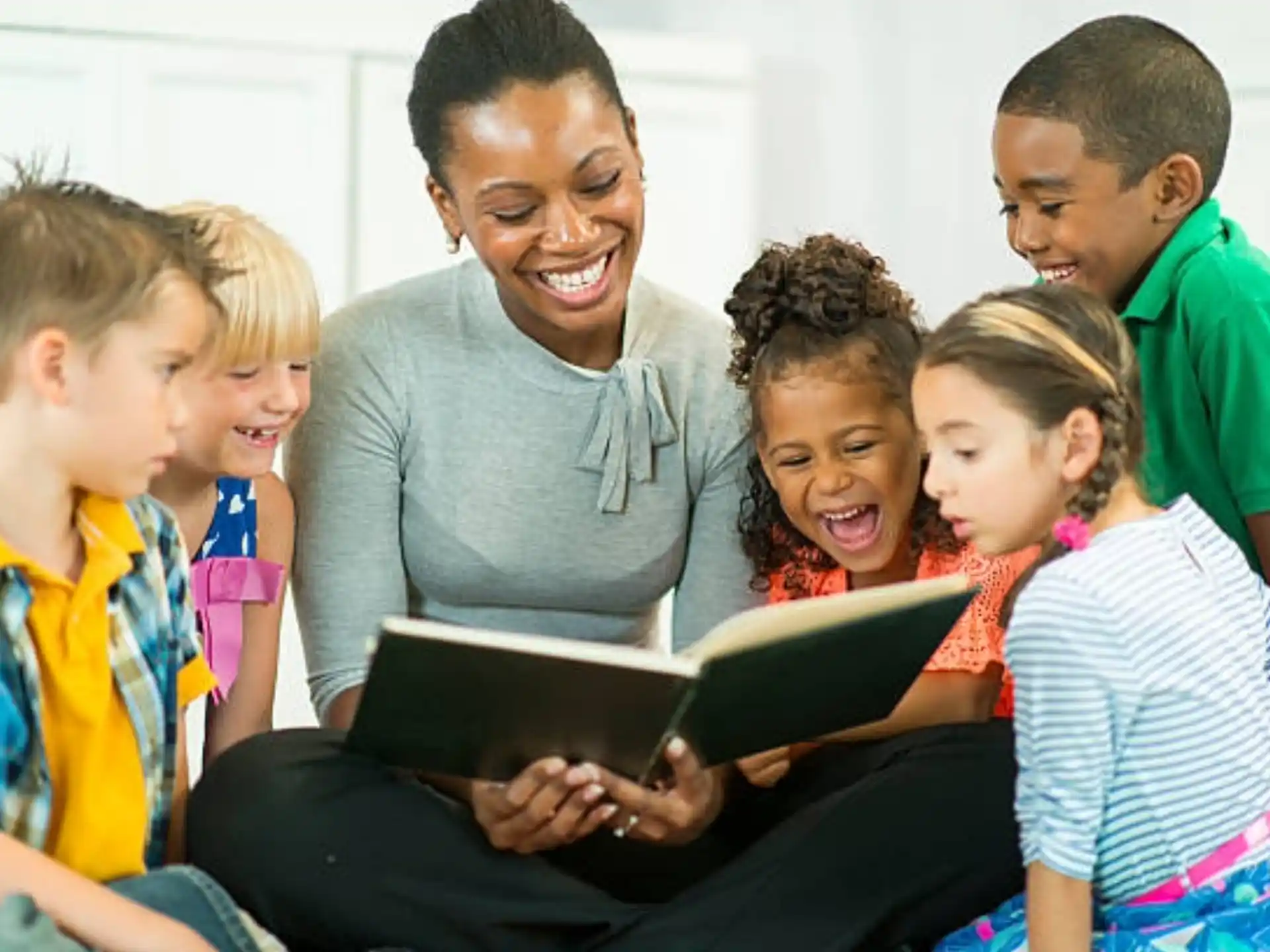 a person reading a book to a group of children