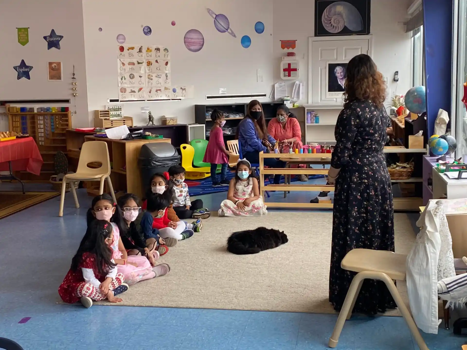 a woman and a group of children in a room with a woman and a cat