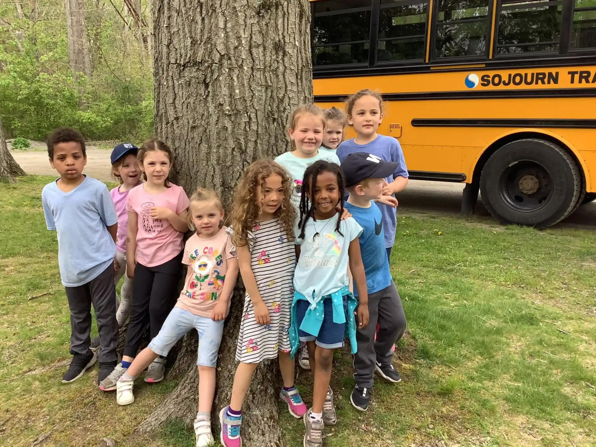 a group of children posing for a photo in front of a tree