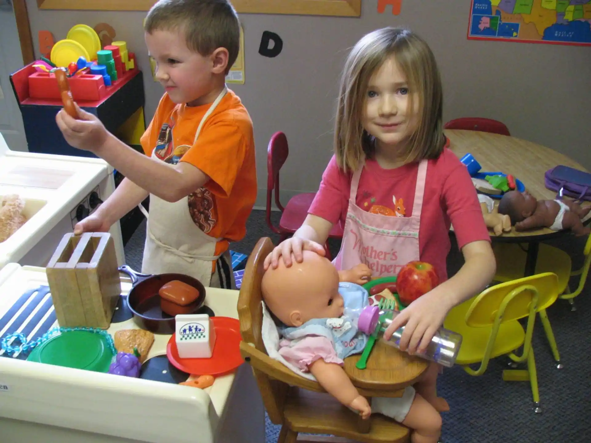 a couple of children sitting at a table with a baby