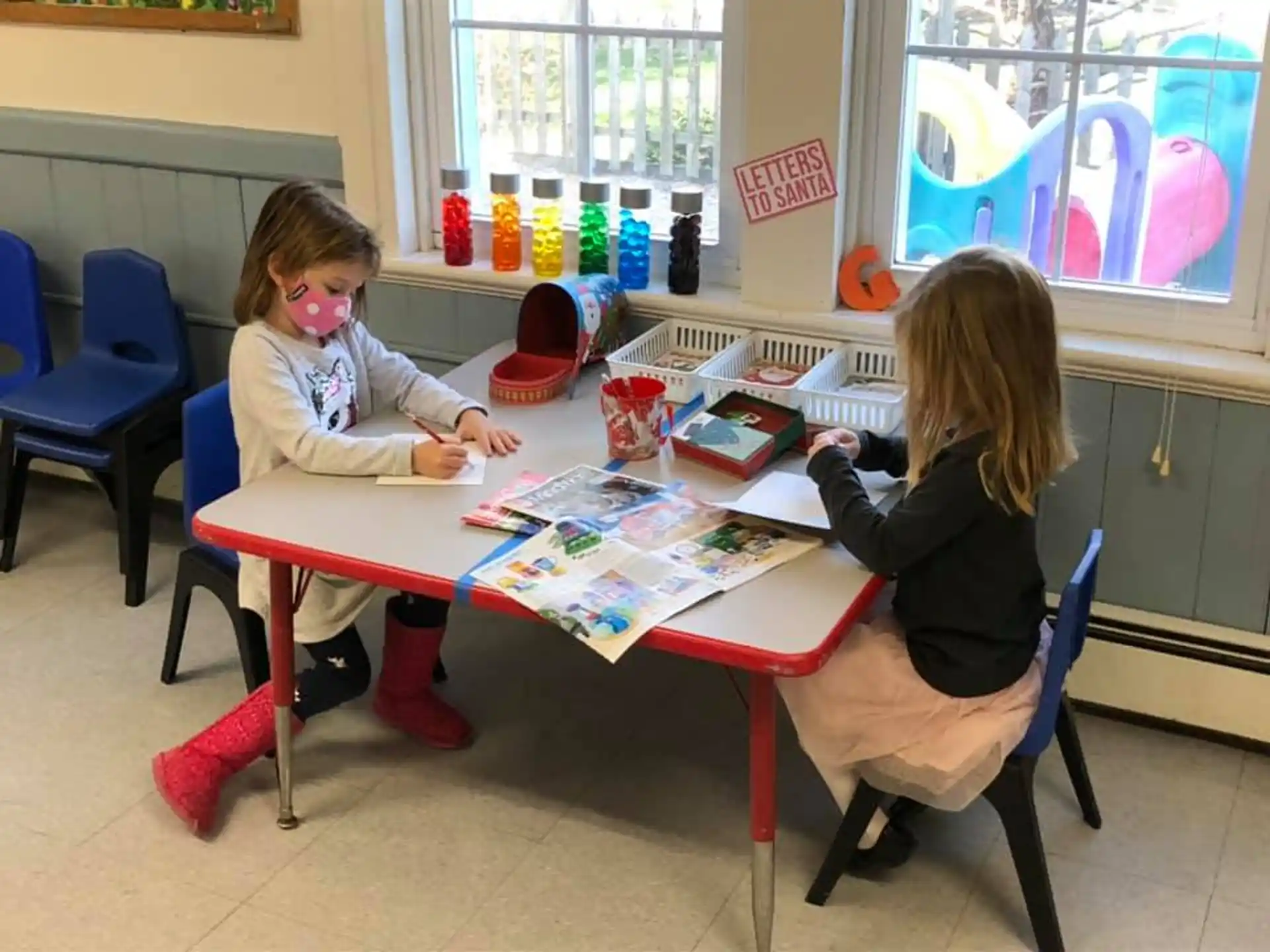 a couple of girls sitting at a table playing a board game