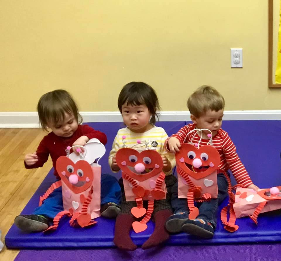 a group of children sitting on a blue mat with stuffed animals