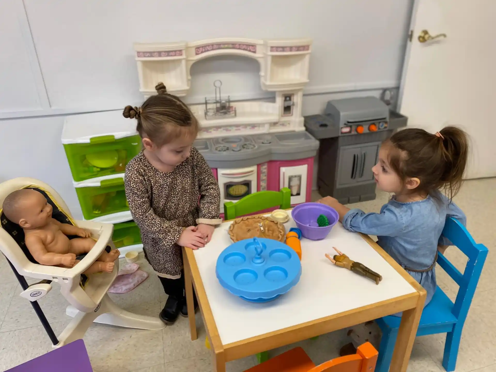 a person and a baby in a room with a table and chairs