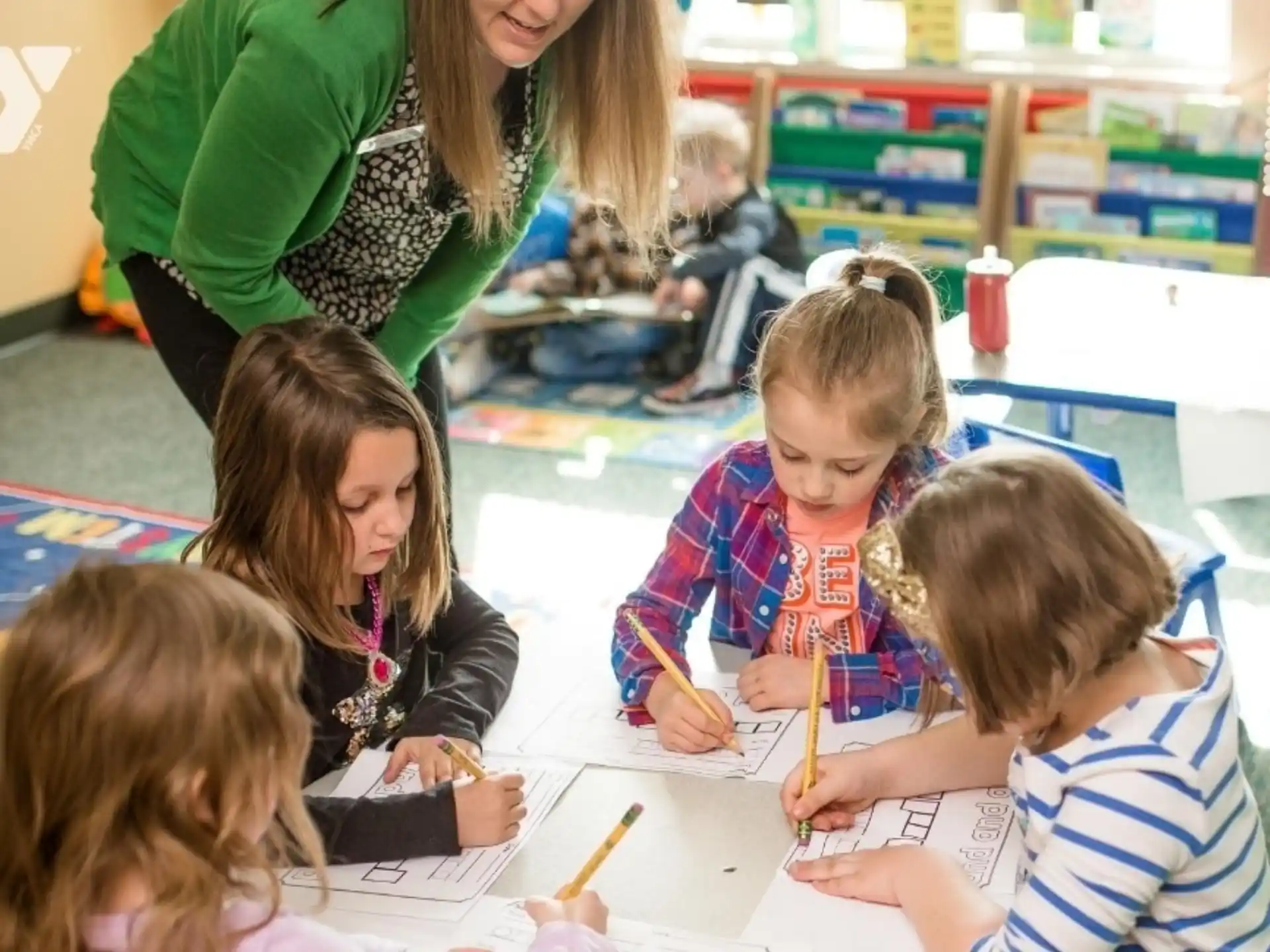 a group of children sitting at a table writing on paper