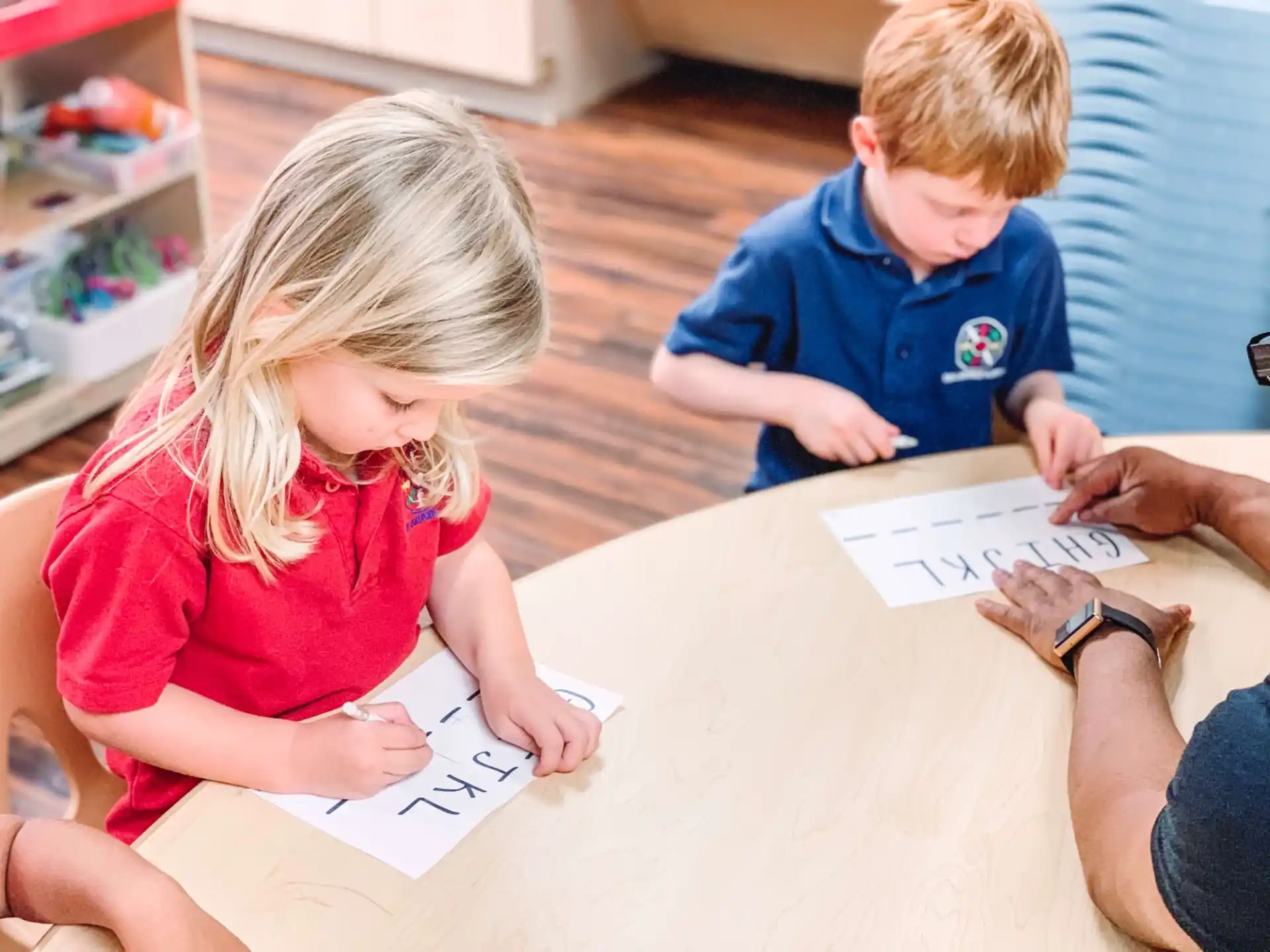 children sitting at a table writing on paper