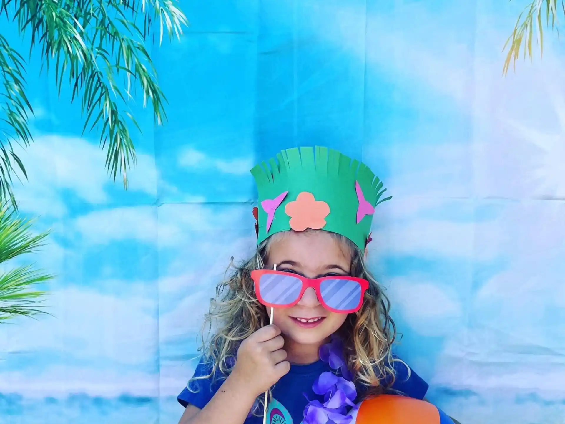 a girl wearing pink glasses and a hat holding a balloon