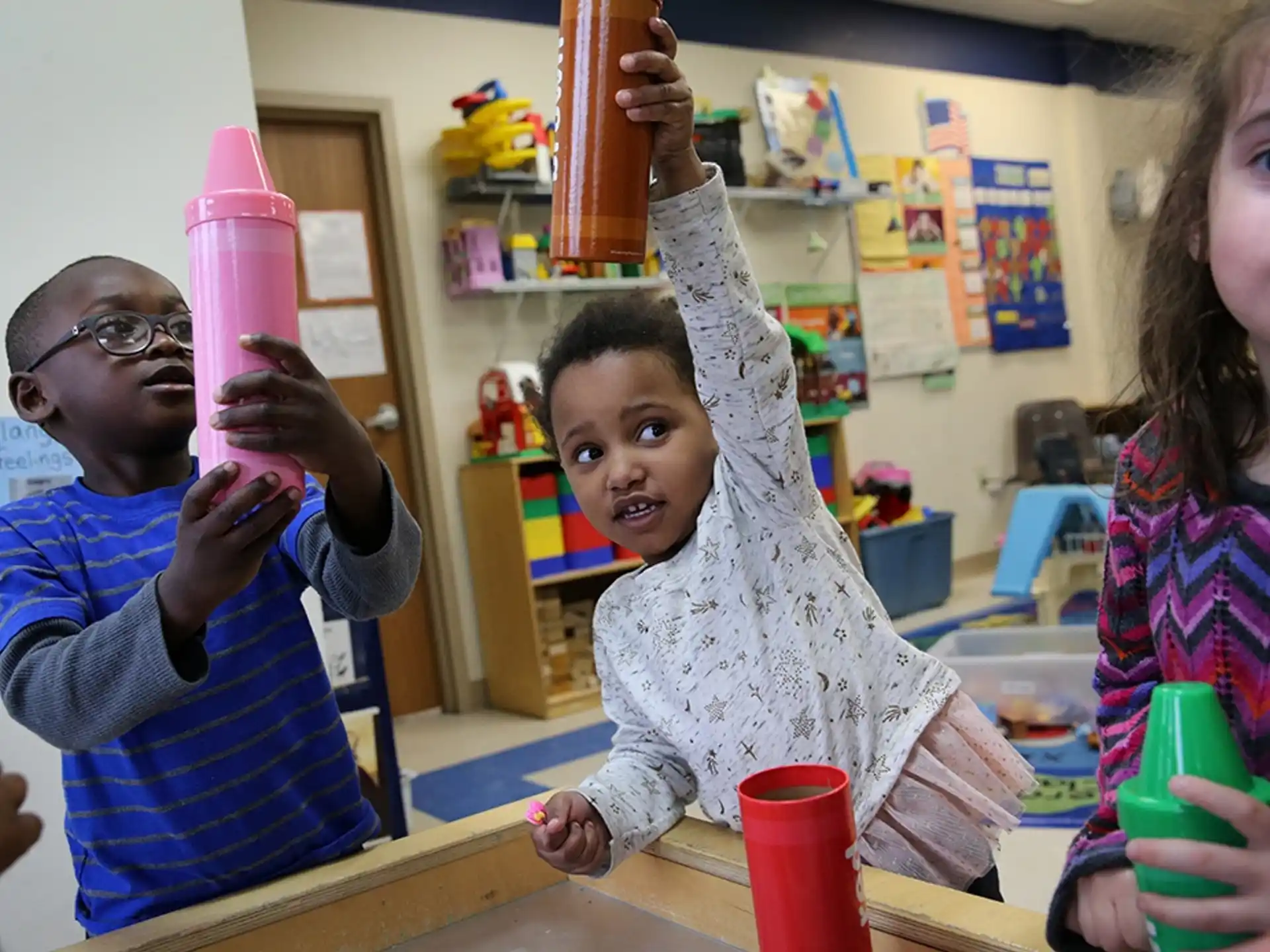a group of kids holding up a pink and white toy