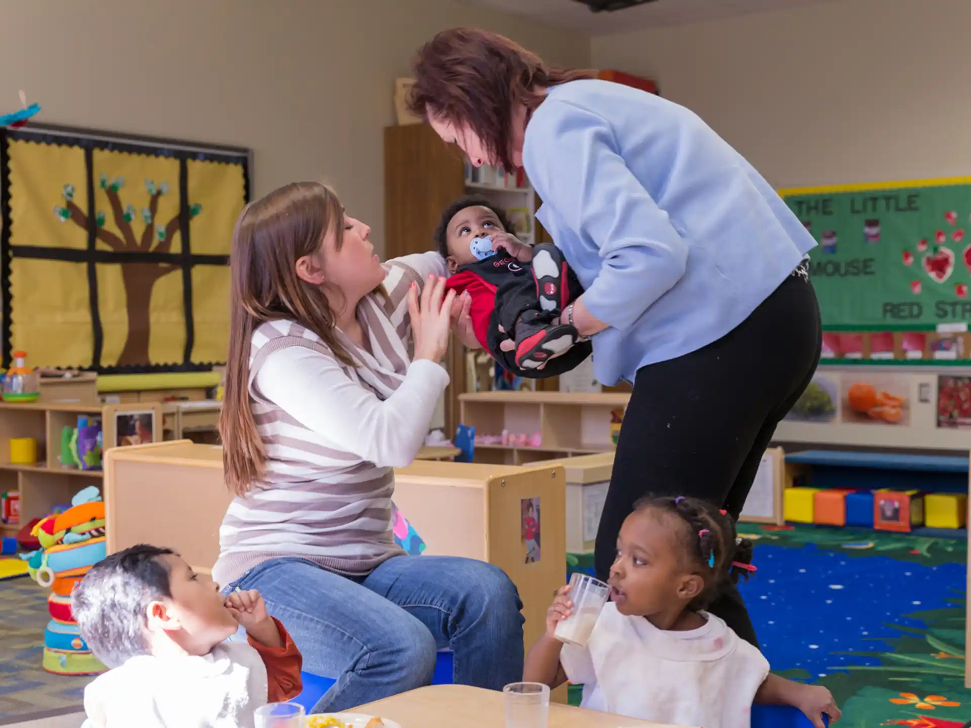 a woman and a group of children in a classroom