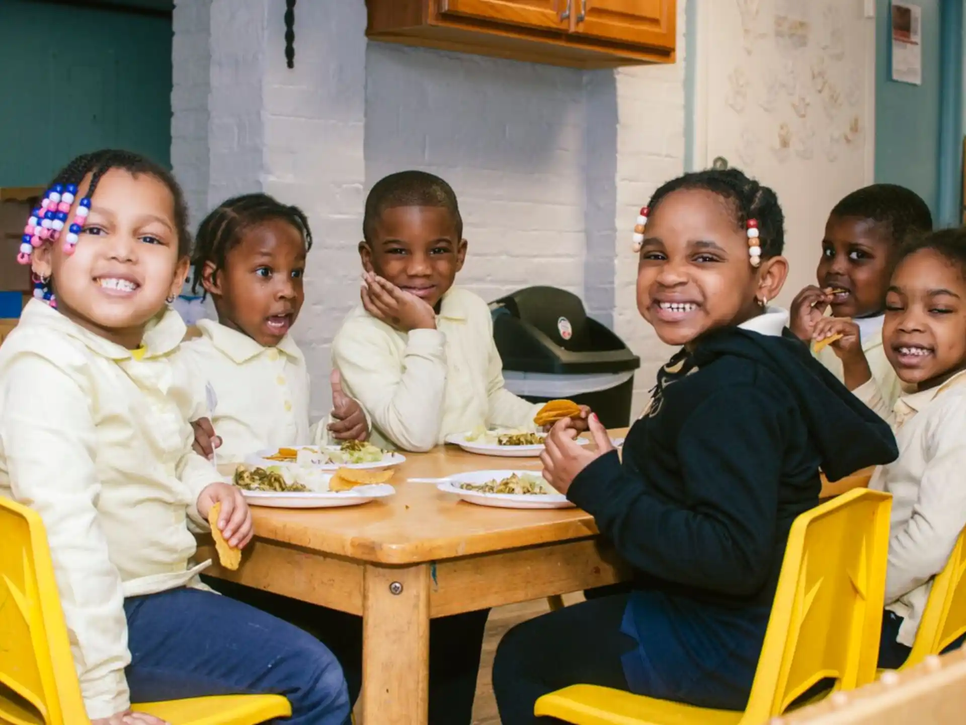 a group of children sitting at a table eating food